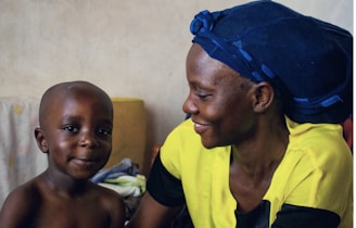 A woman sitting next to a child on a bed