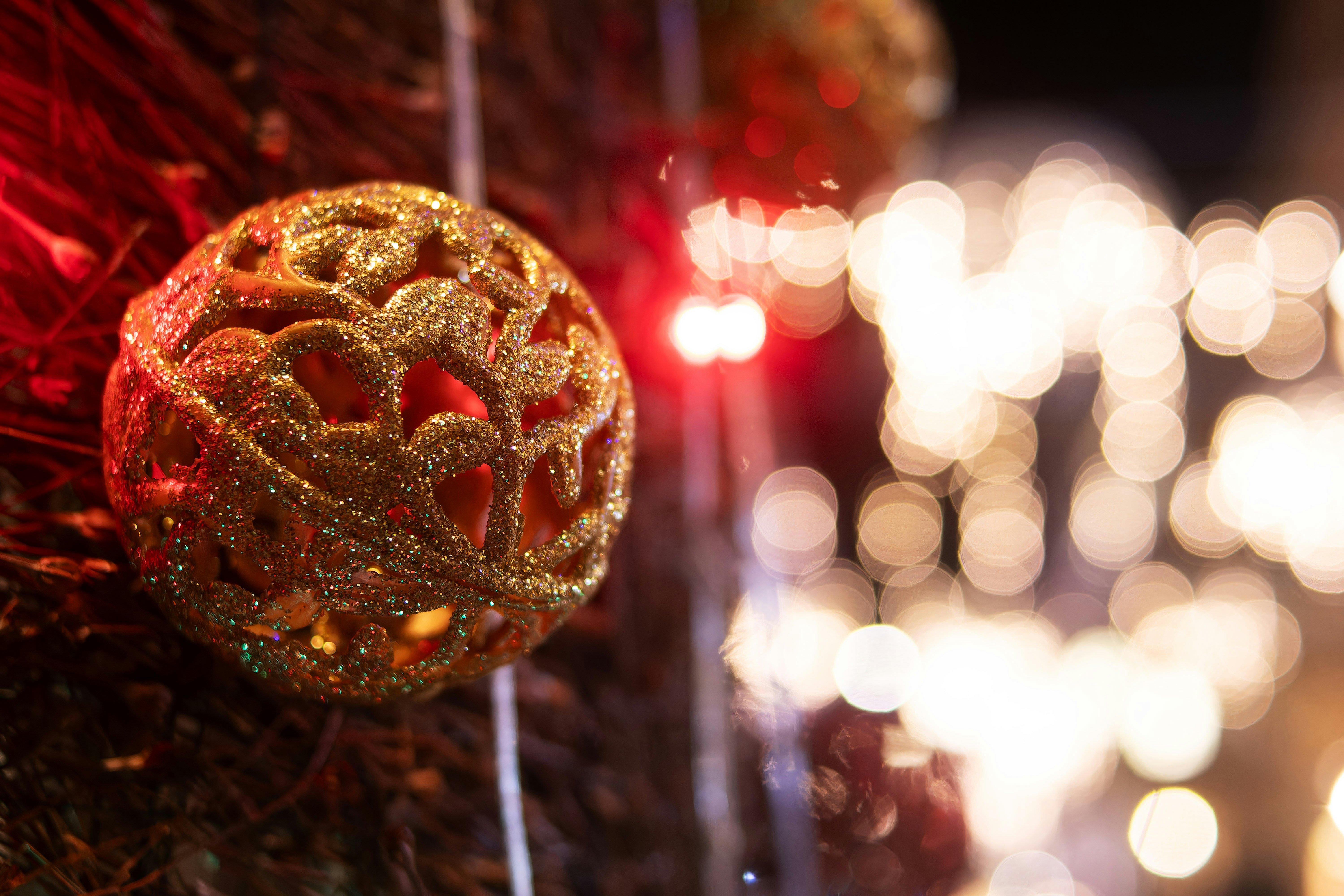 A red and gold ornament hanging from a christmas tree