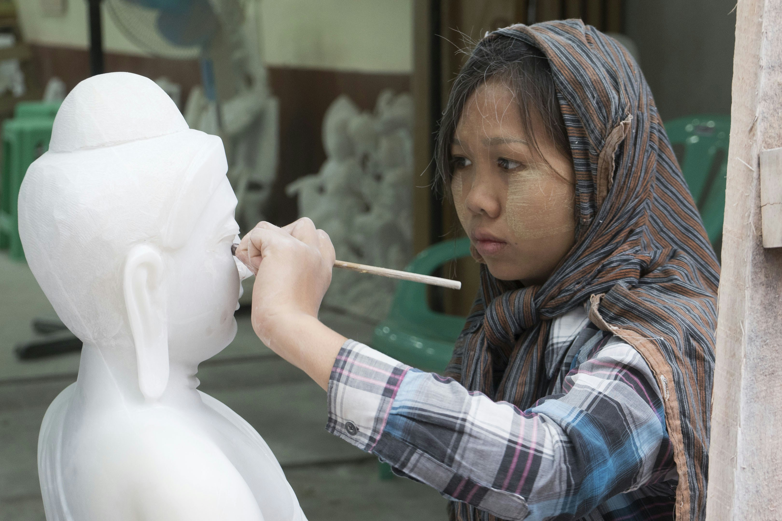 A woman painting a statue of a woman's head
