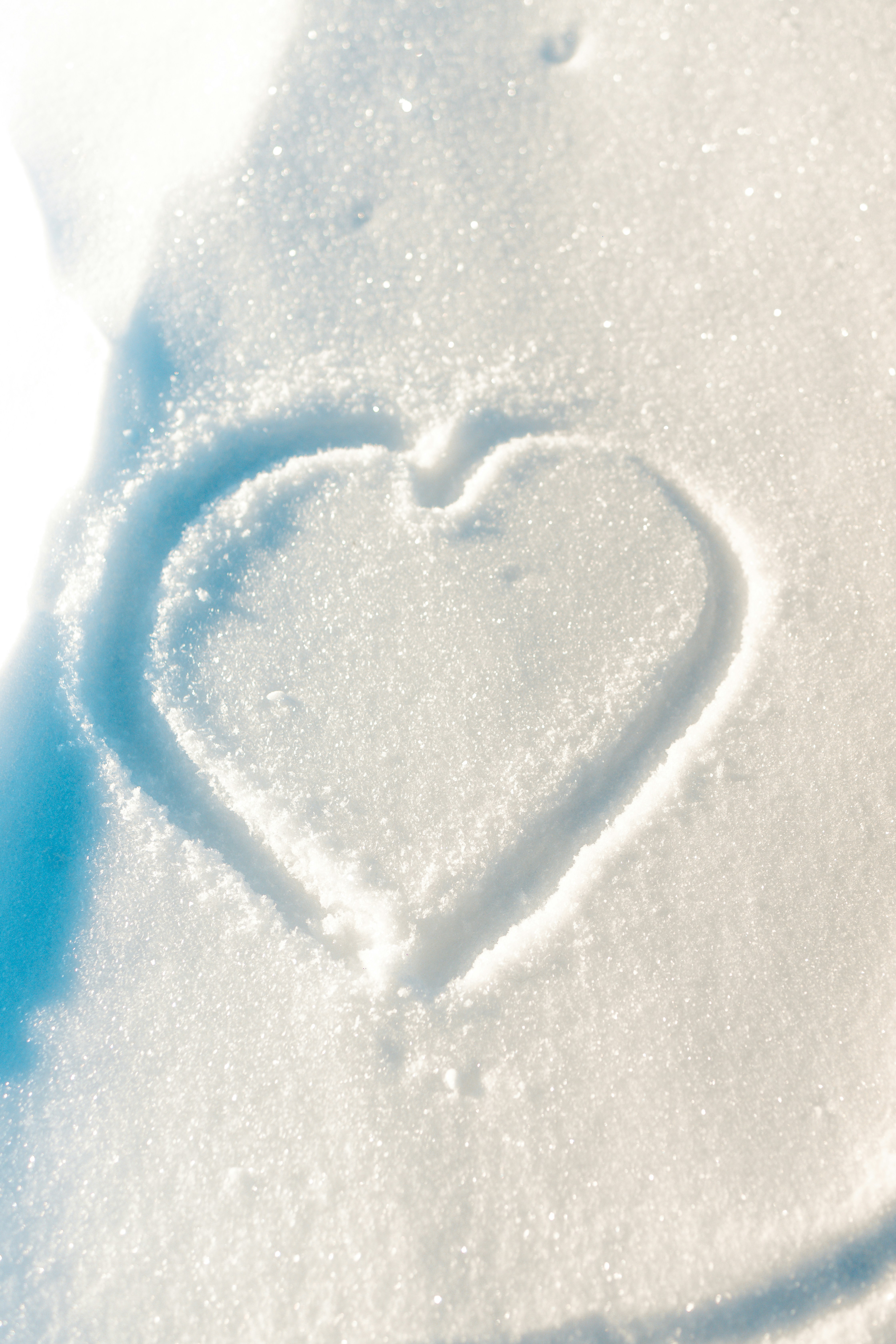 A heart drawn in the snow on a sunny day