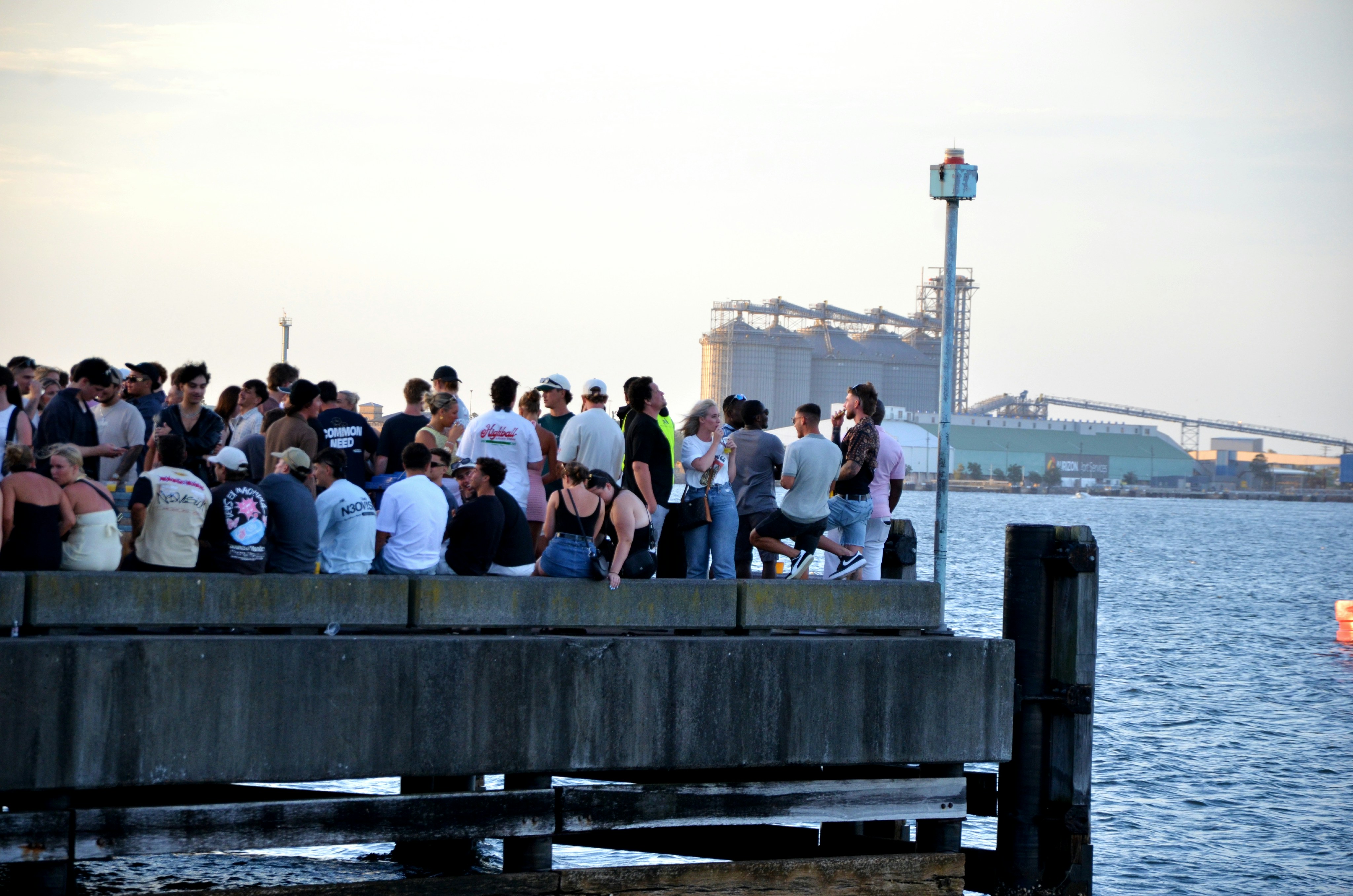 A group of people standing on a pier next to a body of water photo ...