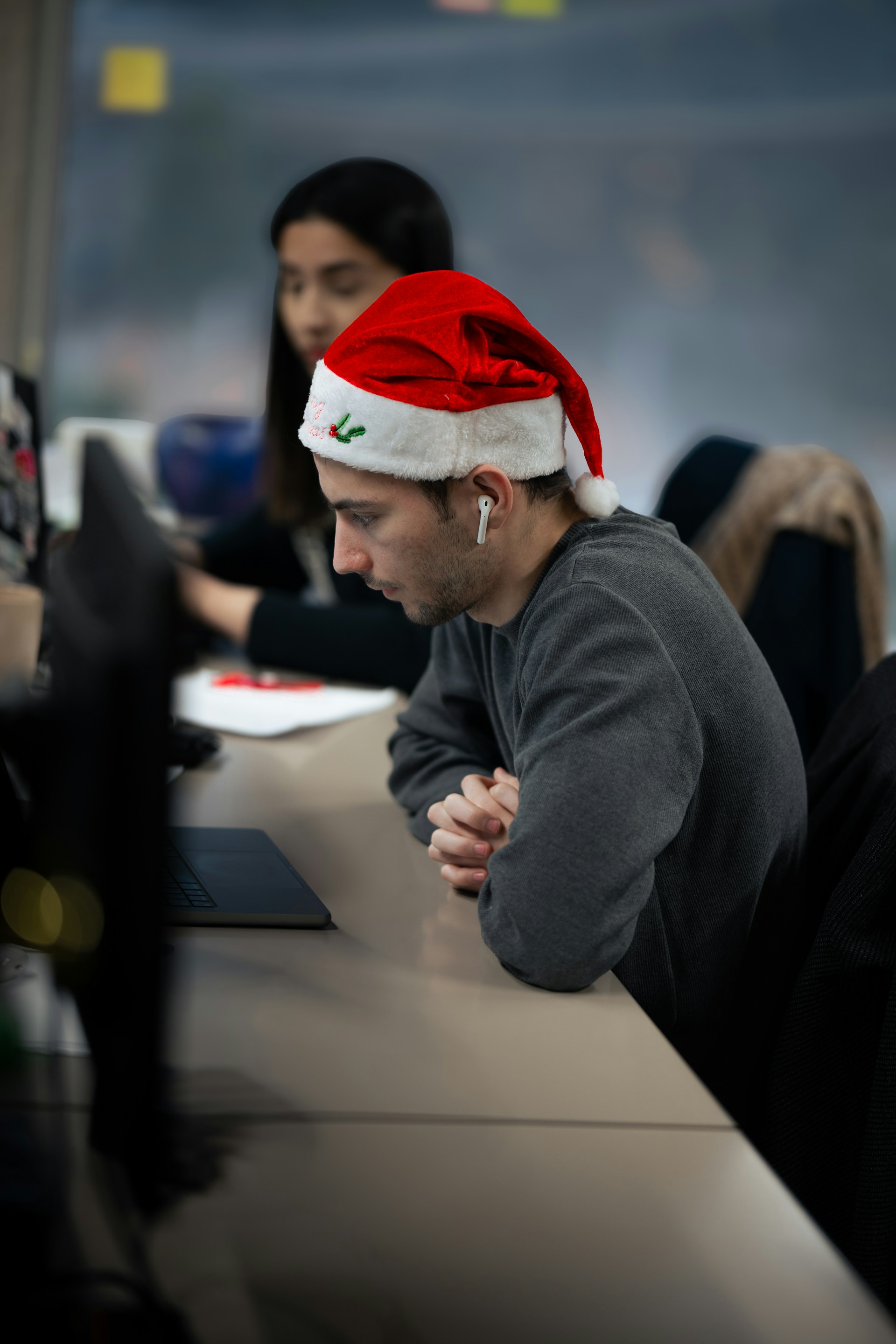A man wearing a santa hat sitting at a desk