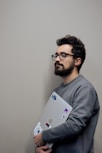 A man with glasses holding a laptop computer