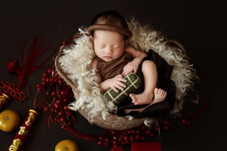 A baby sleeping in a basket with a christmas decoration