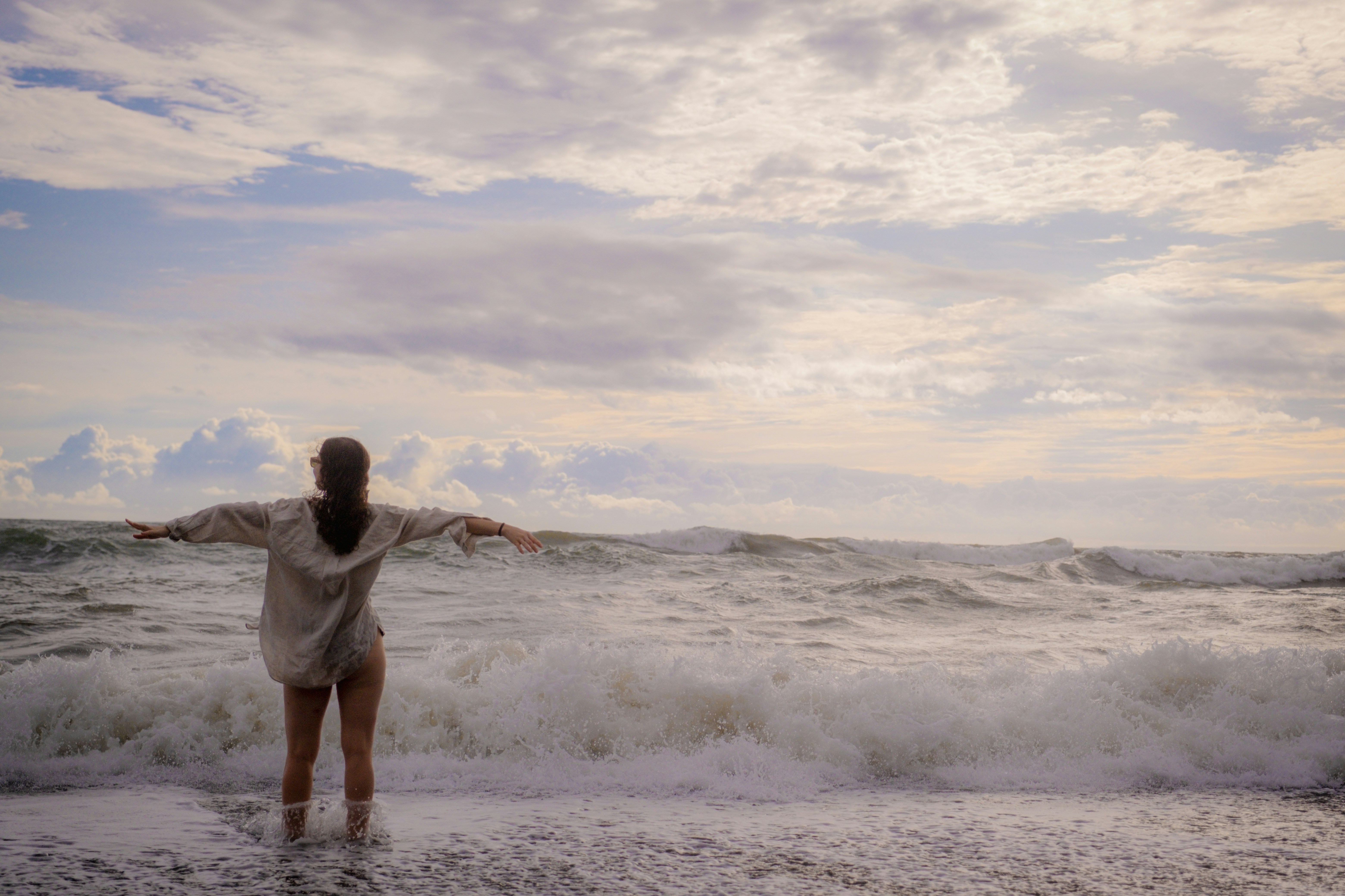 A woman standing on a beach next to the ocean