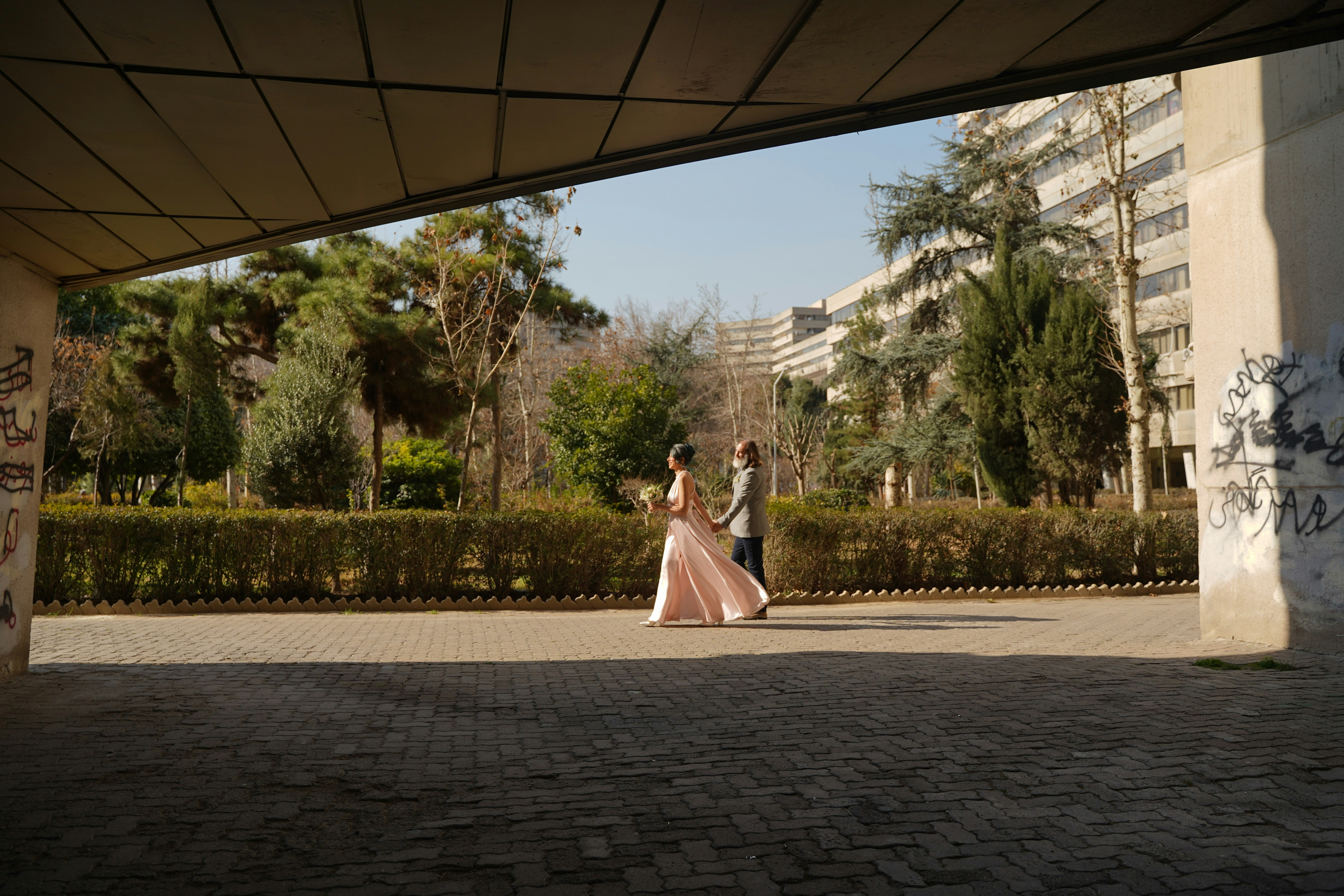 A bride and groom walking under a bridge