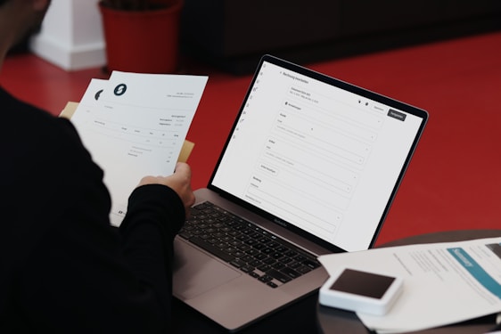 A person sitting at a desk with a laptop and papers