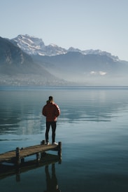 A person standing on a dock in the middle of a lake