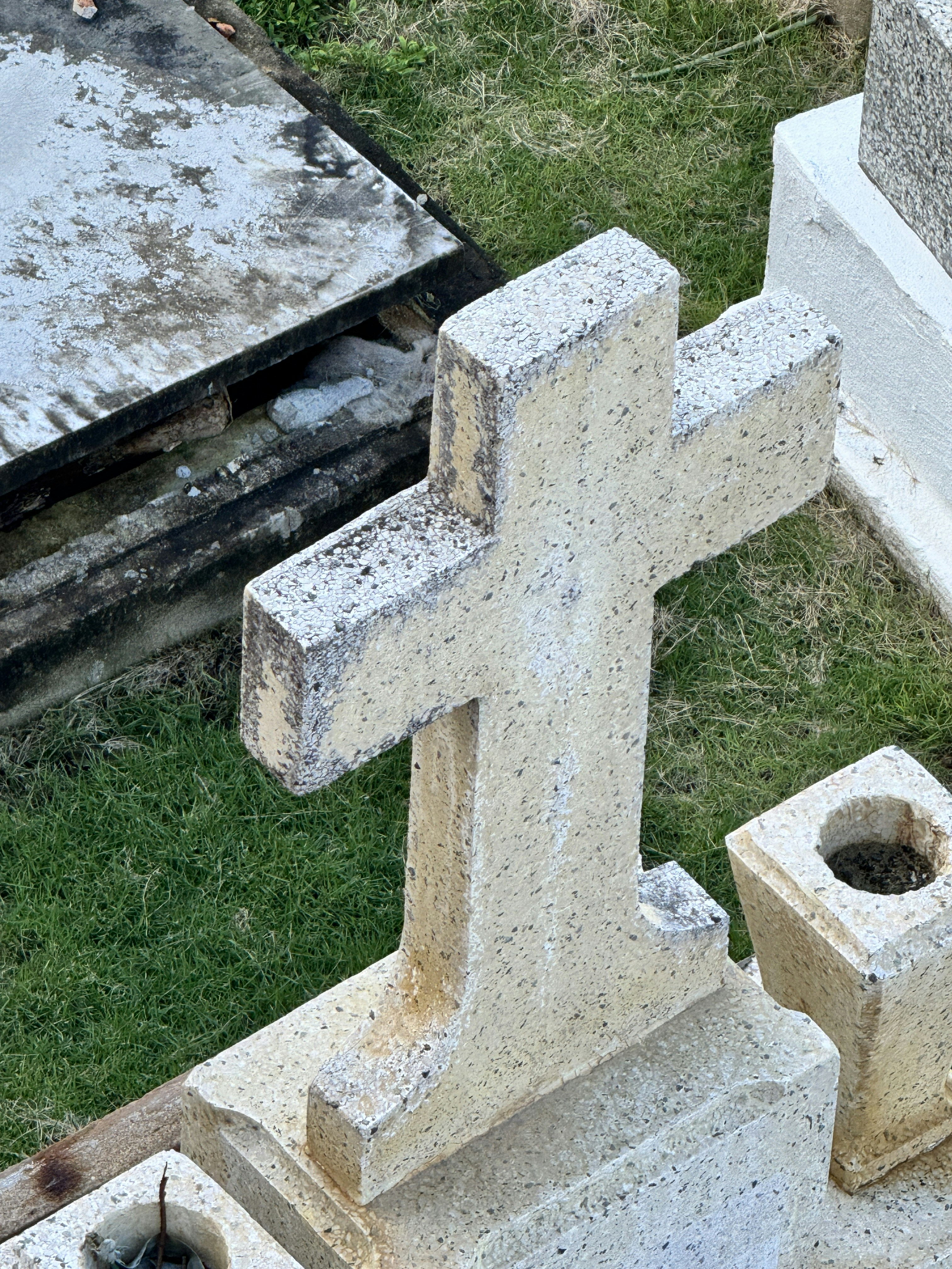 A cement cross sitting on top of a grave