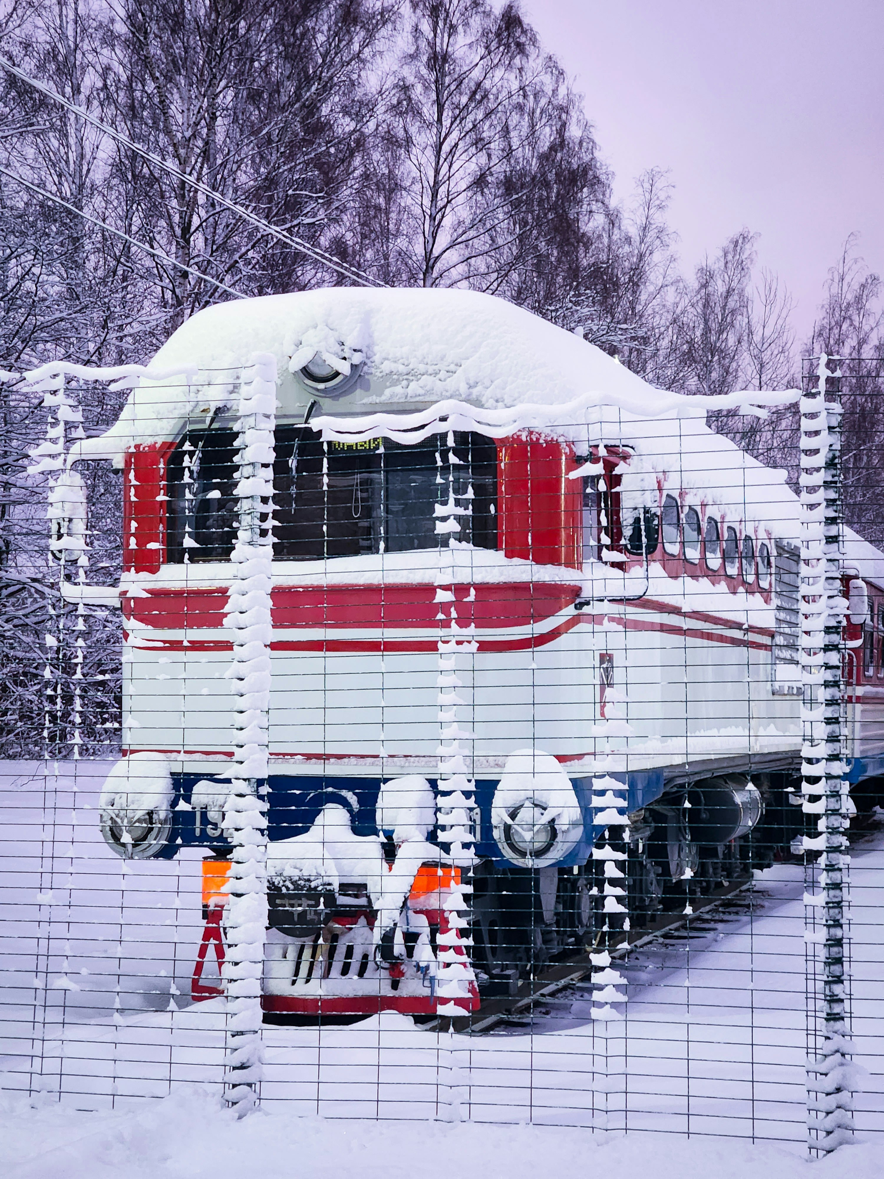 A train car covered in snow behind a wire fence