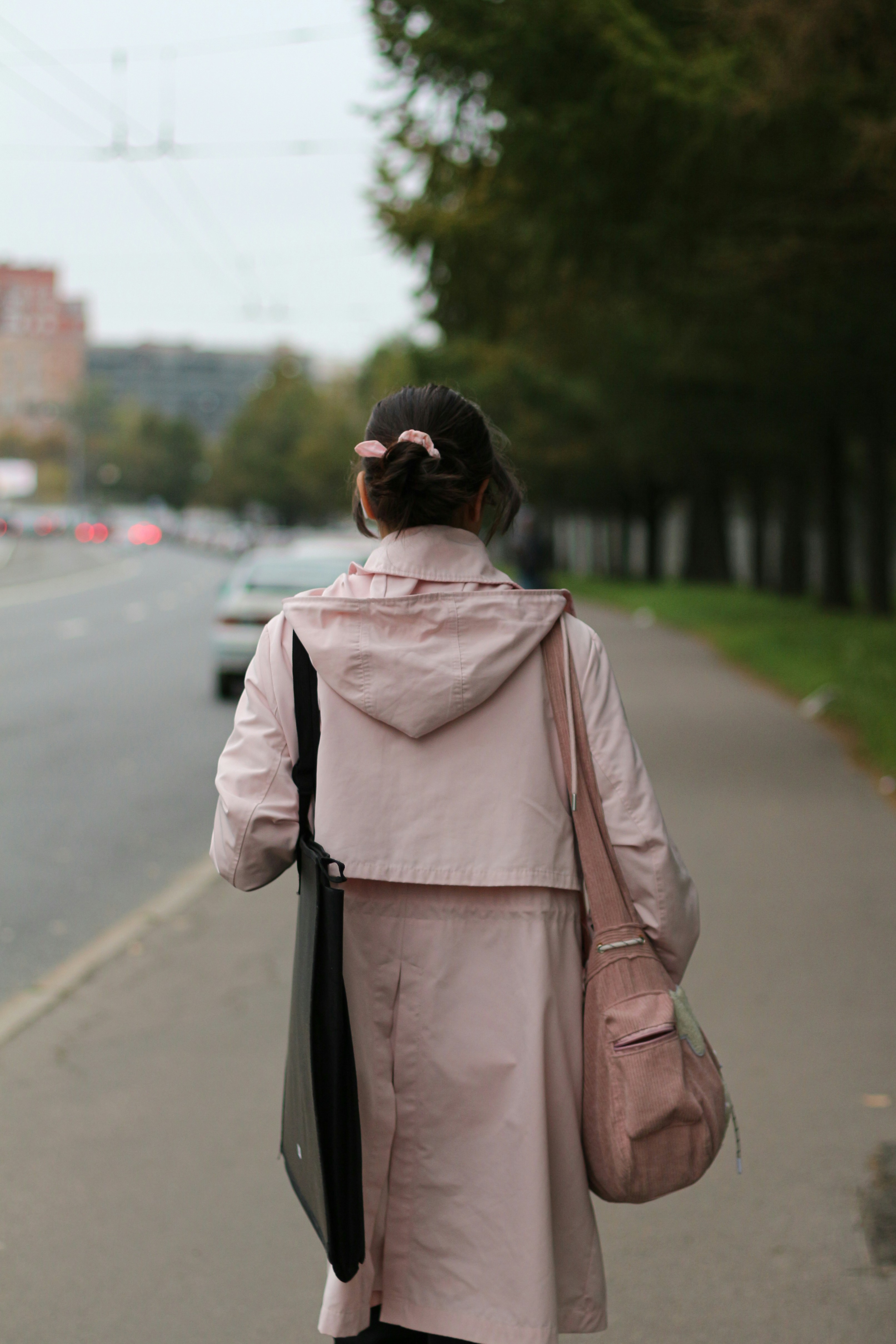 A woman in a pink coat is walking down the street