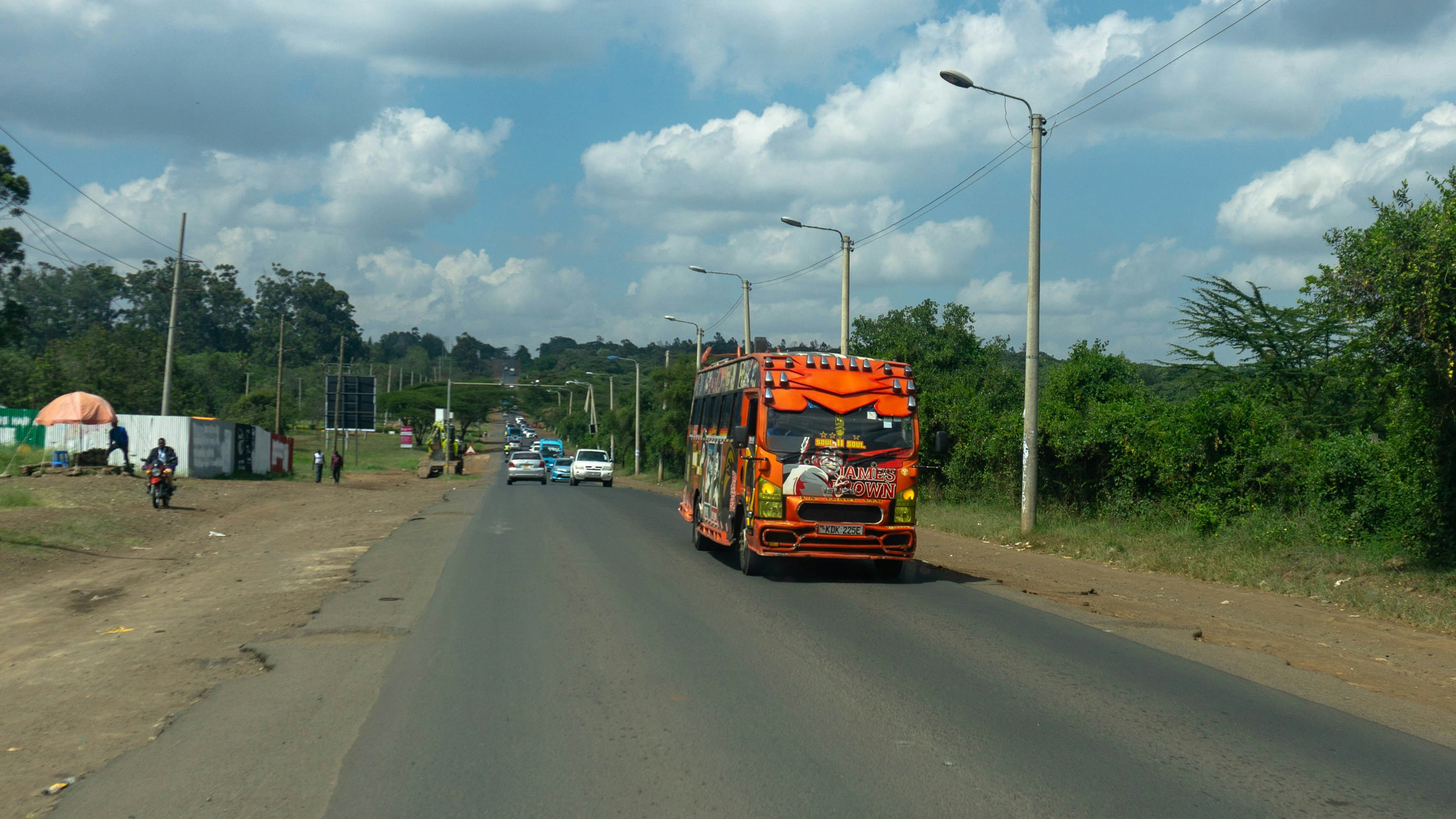 A truck driving down a road next to a forest