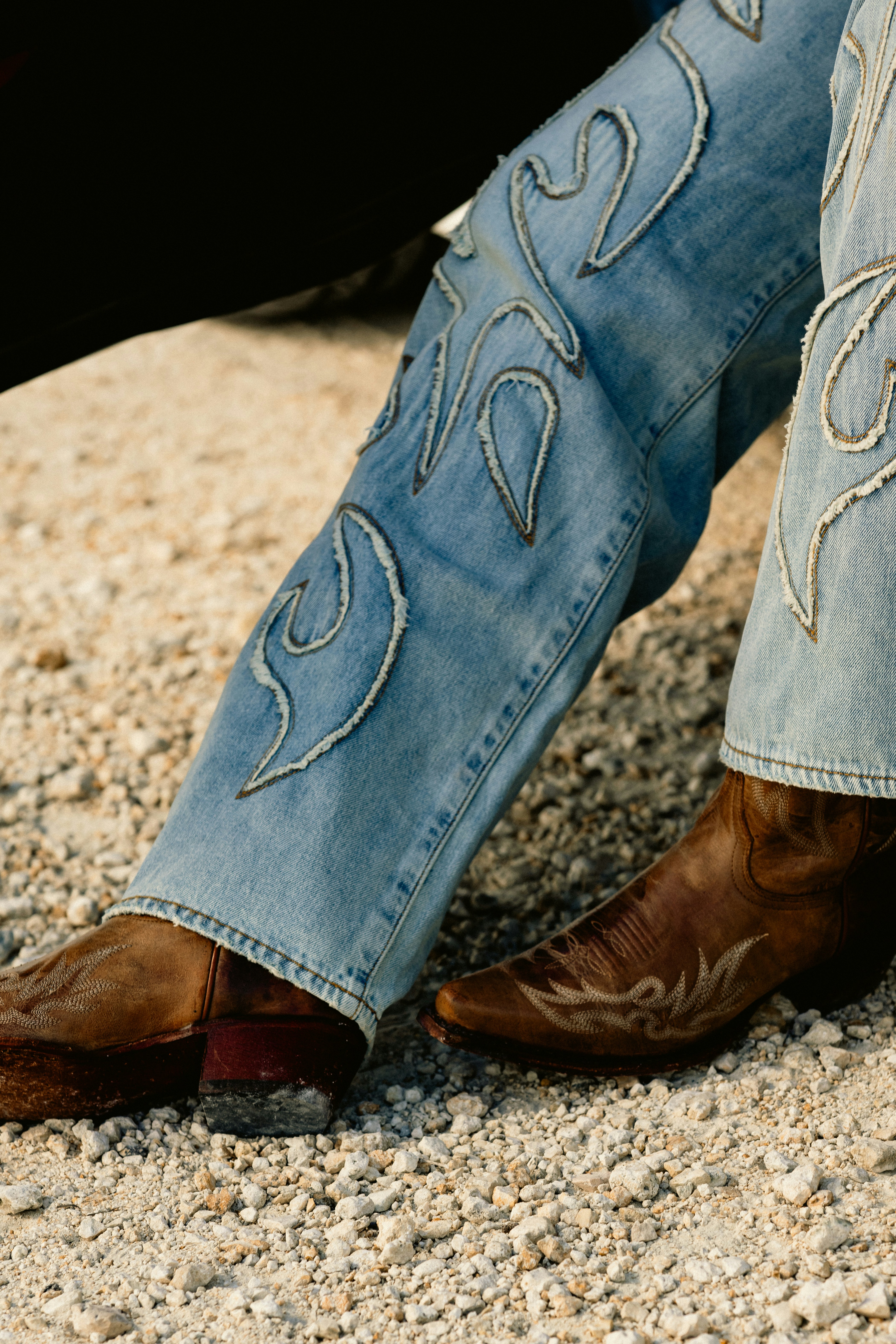 Eine Person mit Cowboystiefeln, die auf dem Boden sitzt