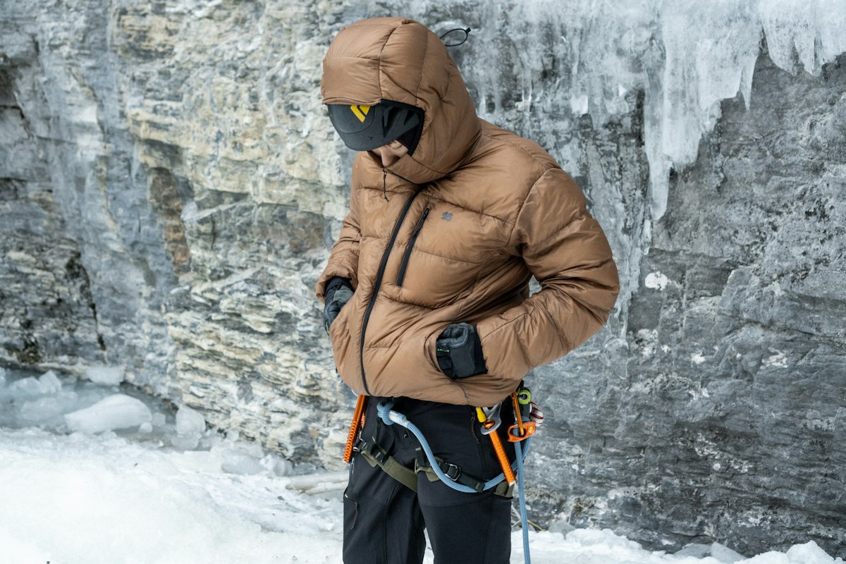 ダウンジャケットを着て氷瀑の前に立つ登山者