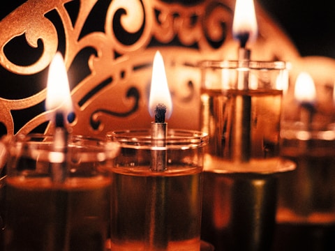 A group of glasses filled with liquid and lit candles