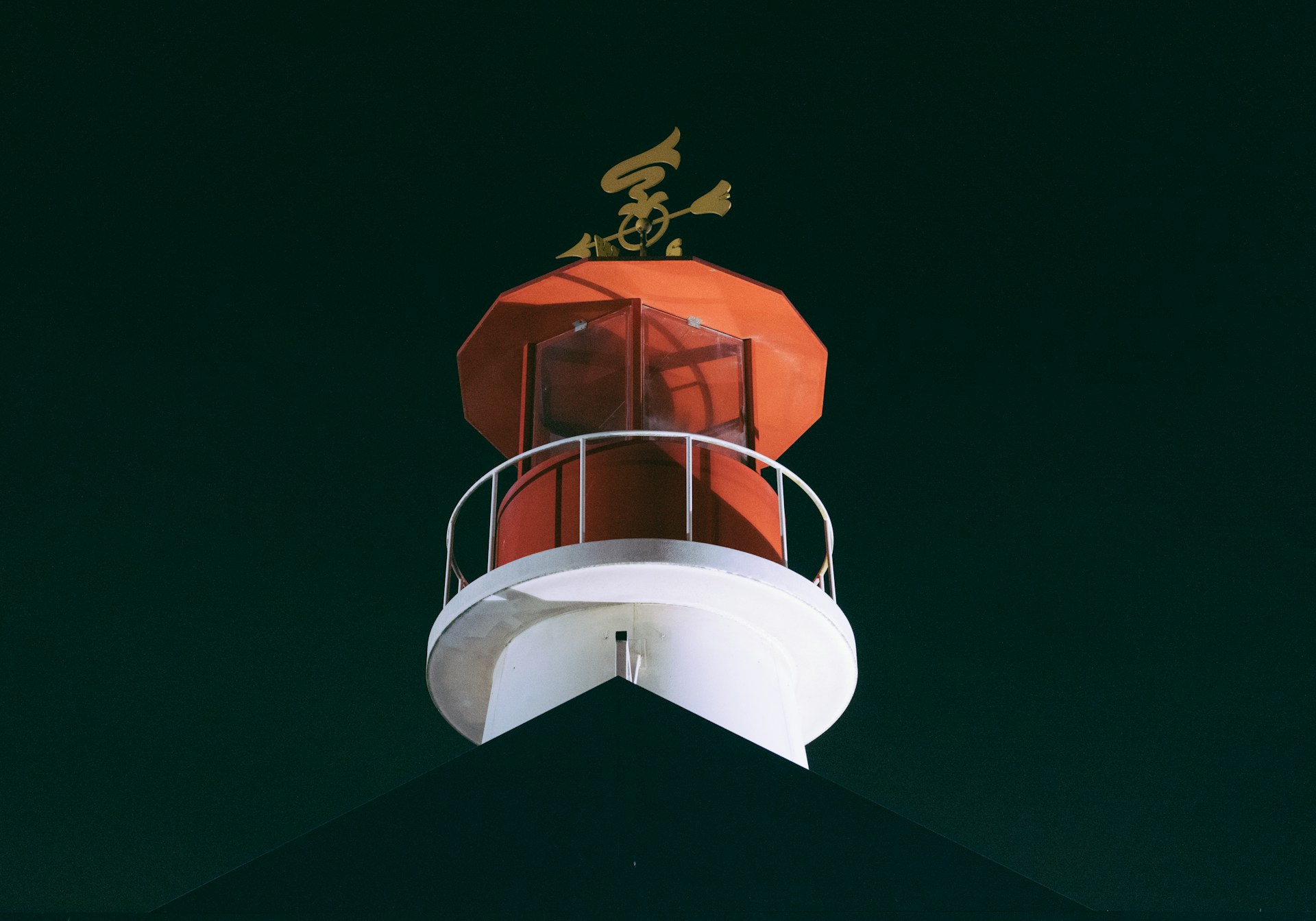 A red and white lighthouse with a gold emblem on top
