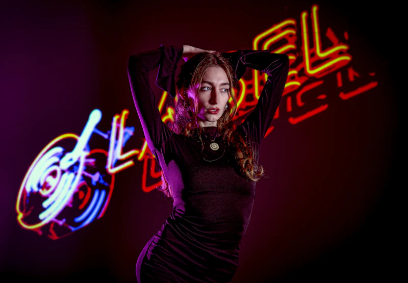 woman in a black dress with a neon sign