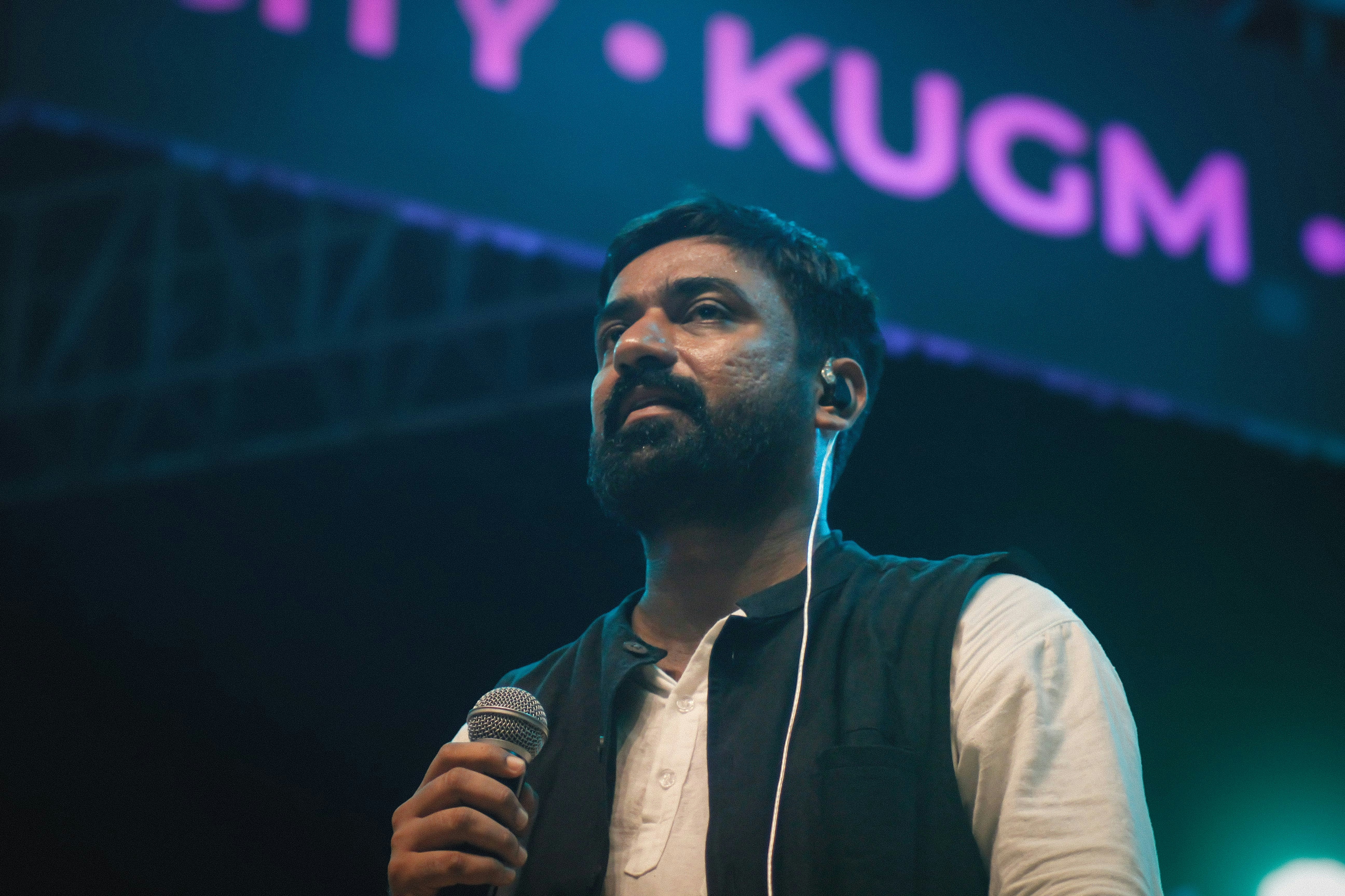A man speaking into a microphone in front of a sign