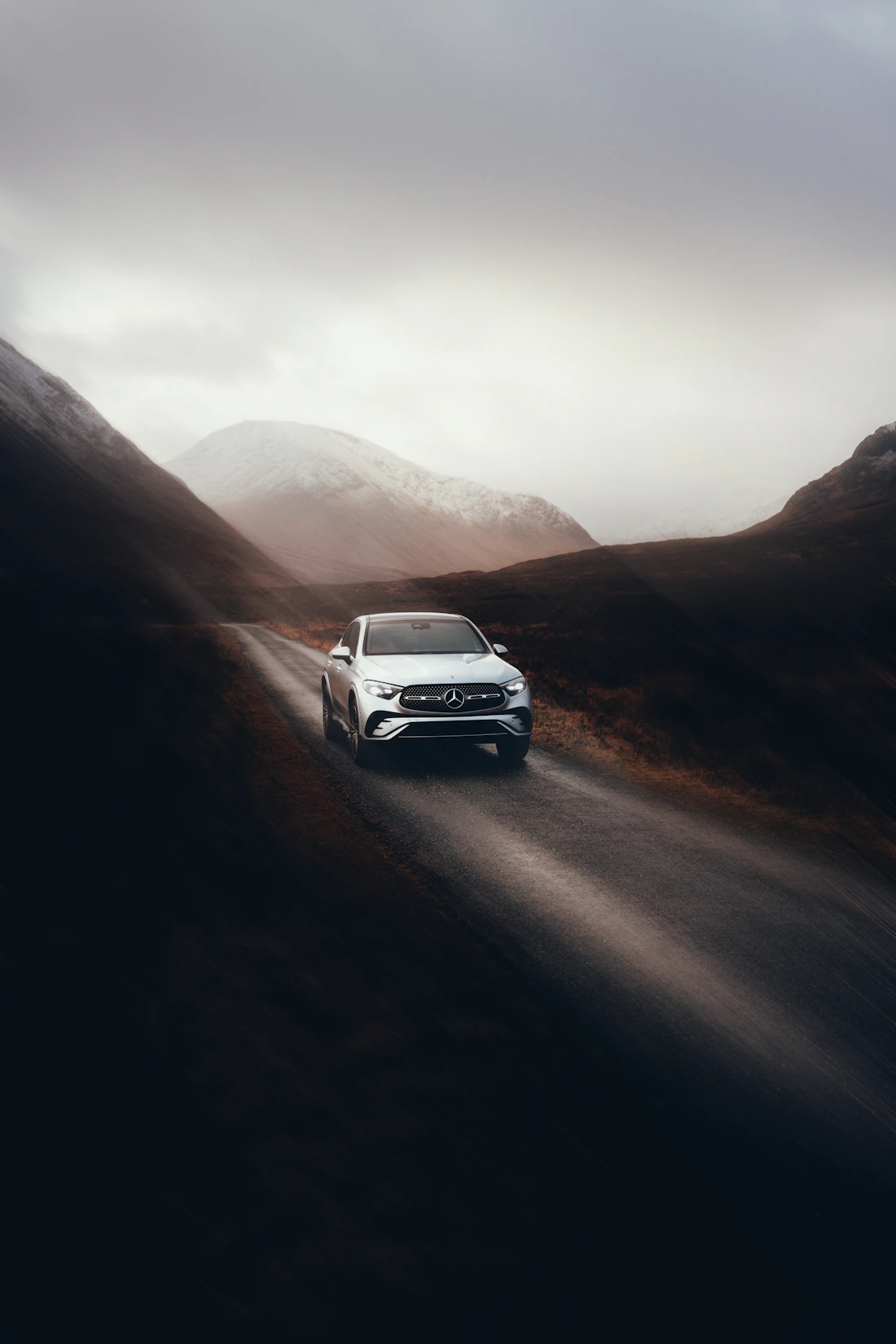 Auto blanco circulando por un camino de montaña