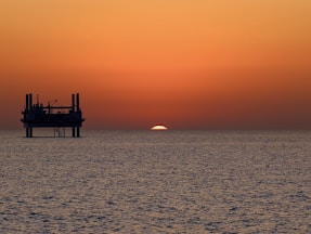 The sun is setting over the horizon of the ocean