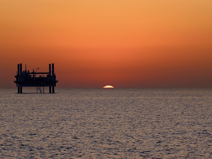 The sun is setting over the horizon of the ocean