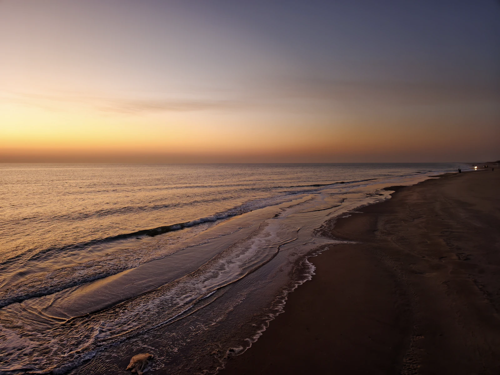 The sun is setting over the ocean and the beach