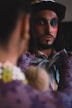 A man with a painted face is looking in a mirror