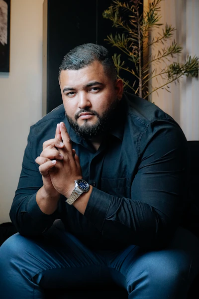 A man sitting on a couch with his hands clasped