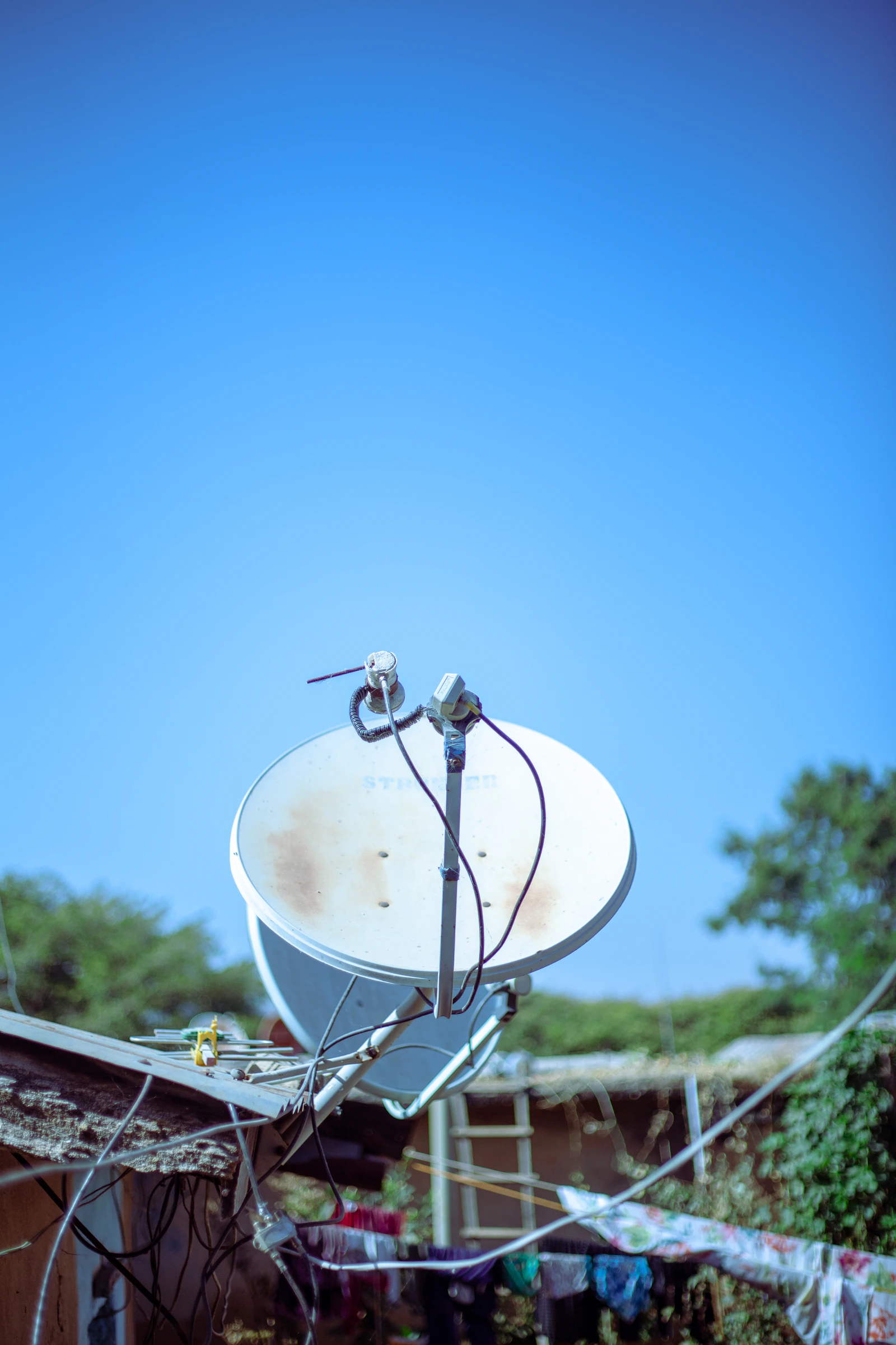 Satellite dish mounted at a rural property under a wide open sky