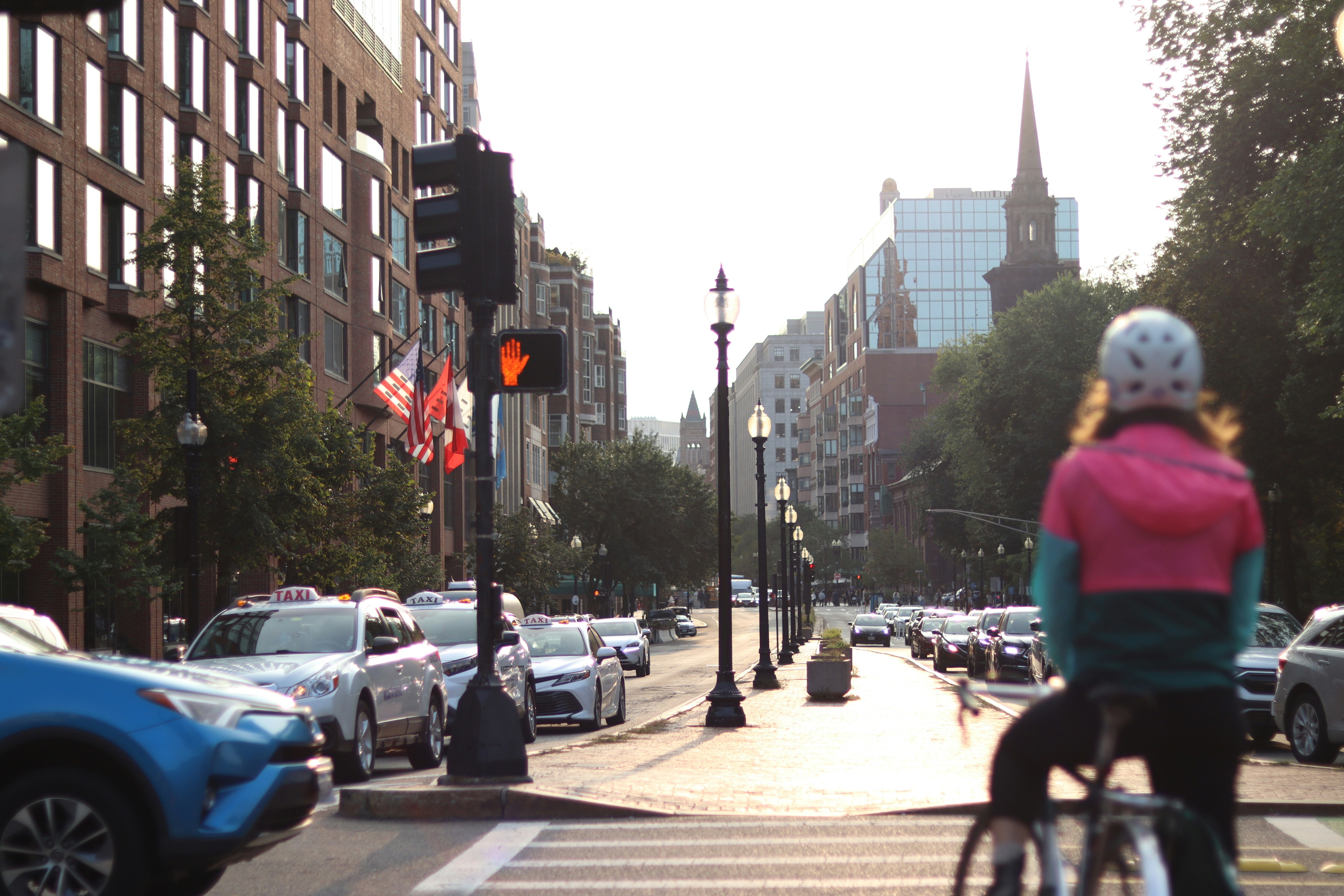 A woman riding a bike down a street next to tall buildings