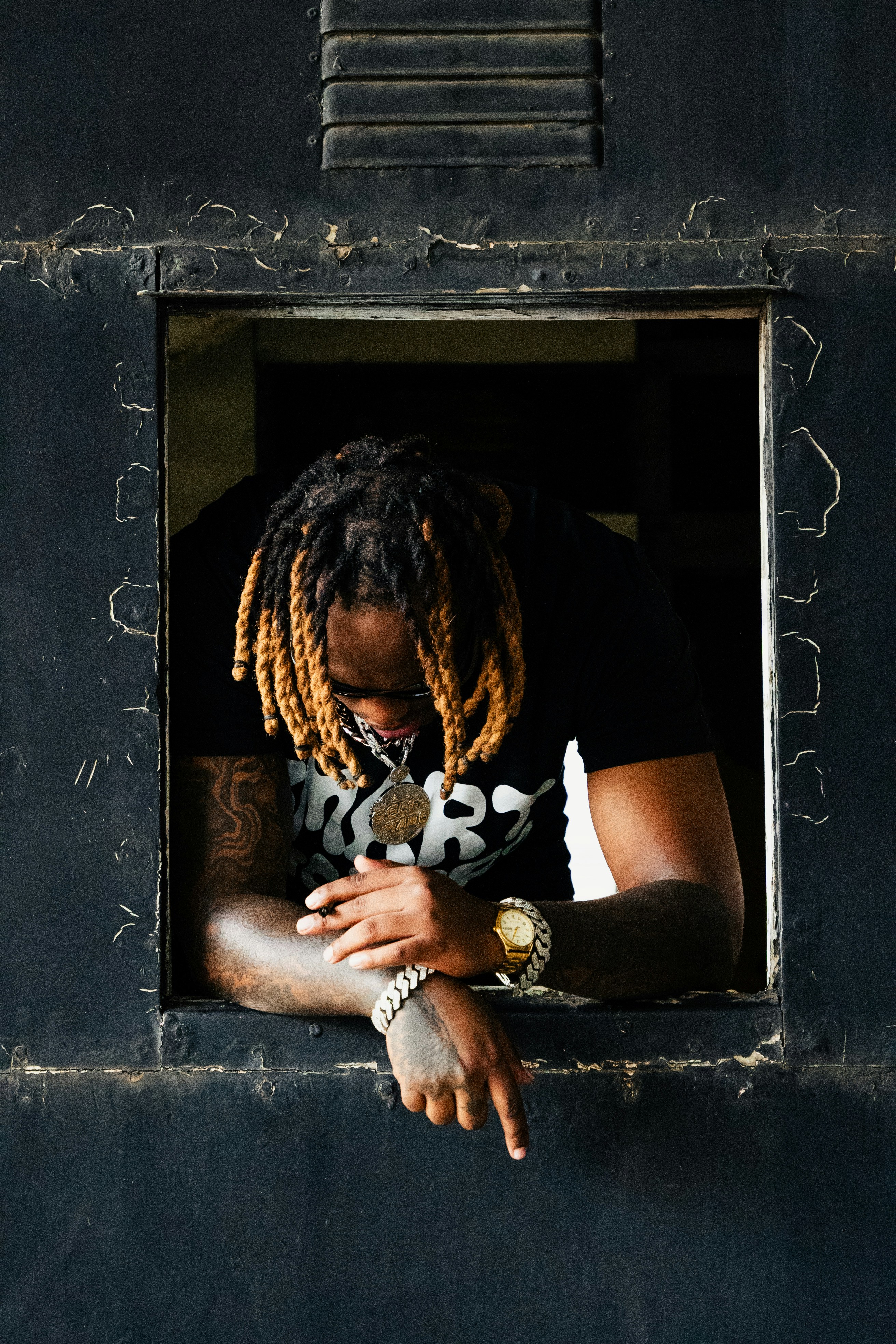 A man with dreadlocks looking out of a window