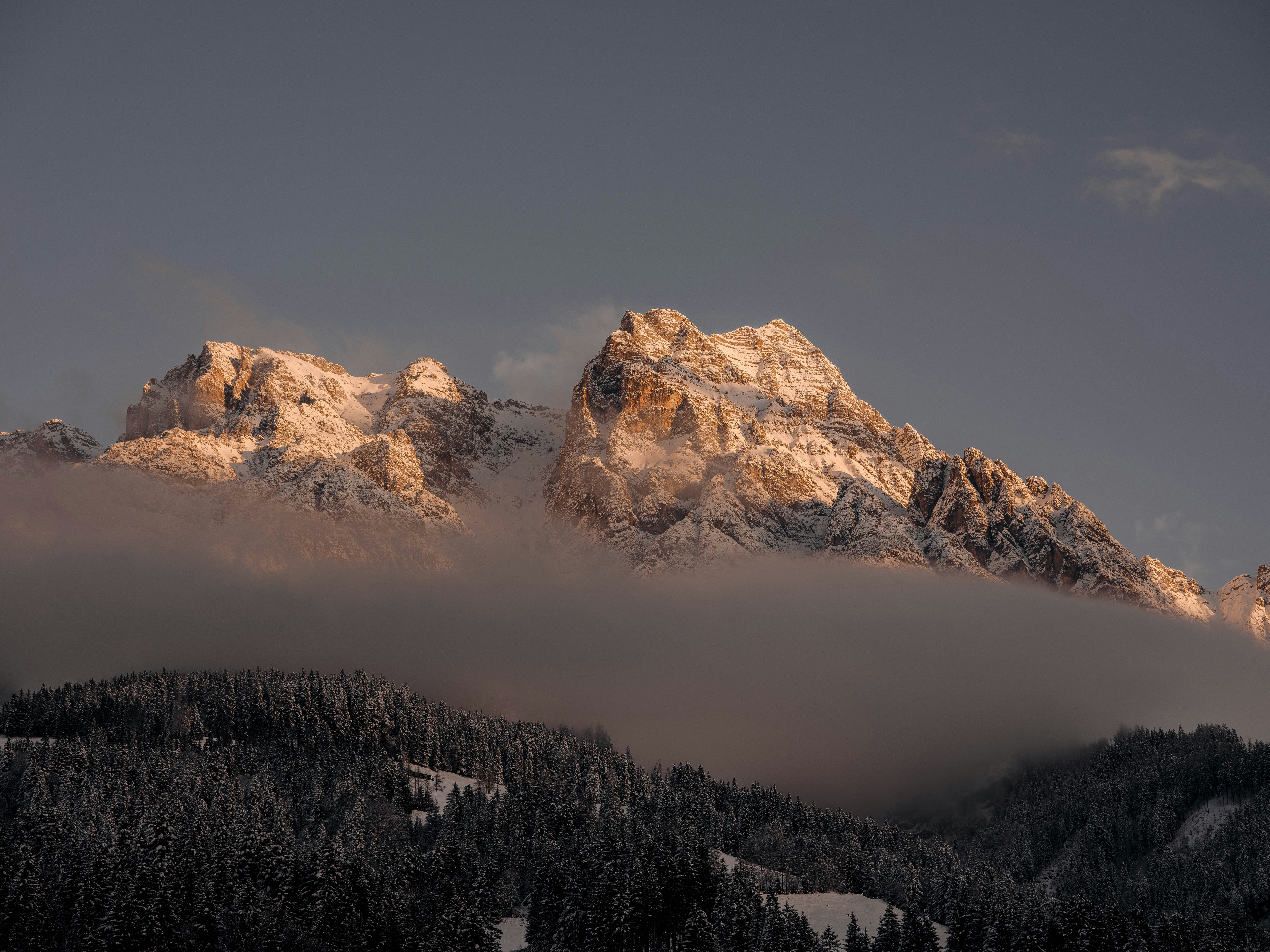 Ein schneebedeckter Berg mit Wolken im Vordergrund