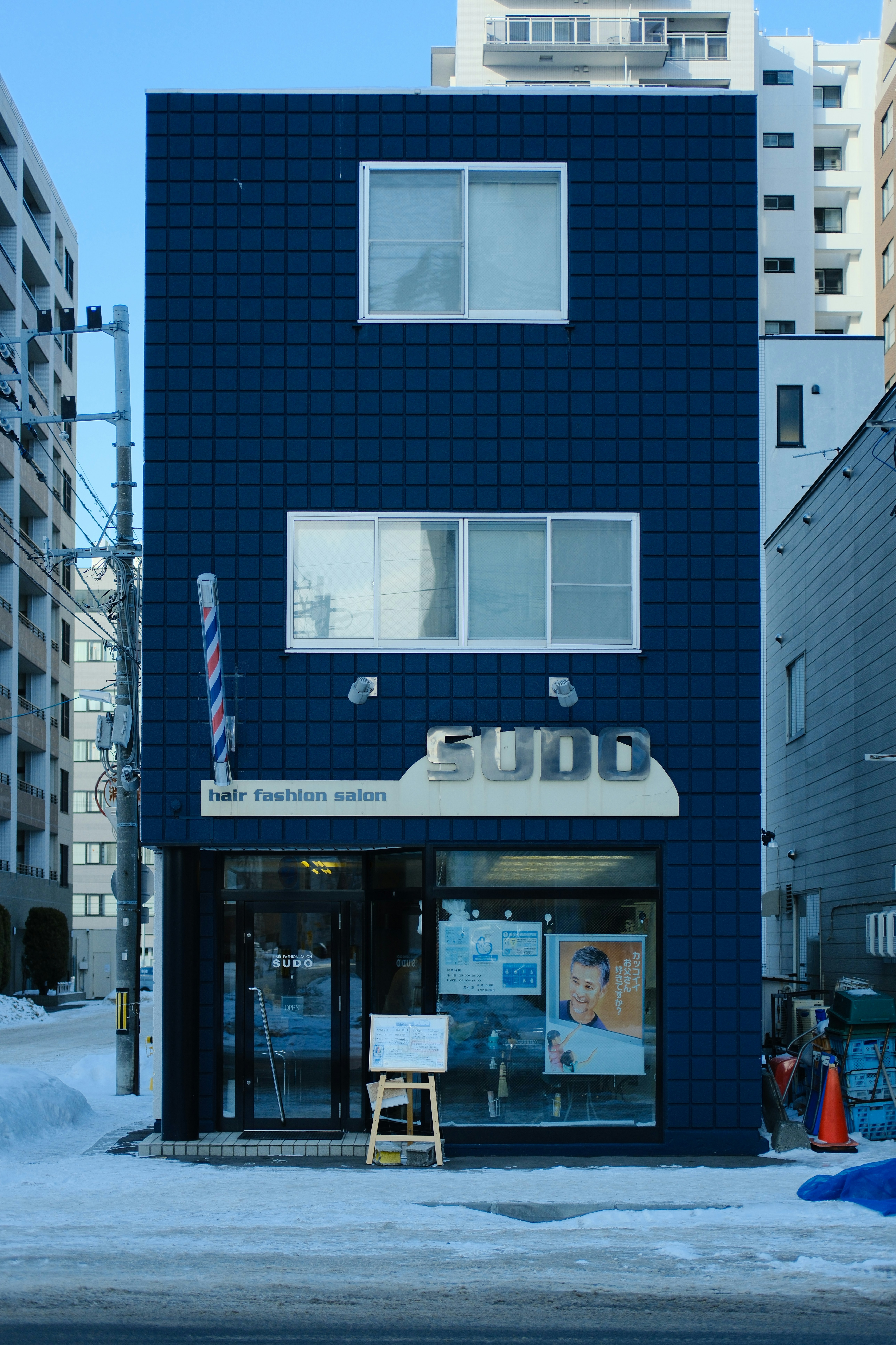 道路脇に佇む背の高い青い建物