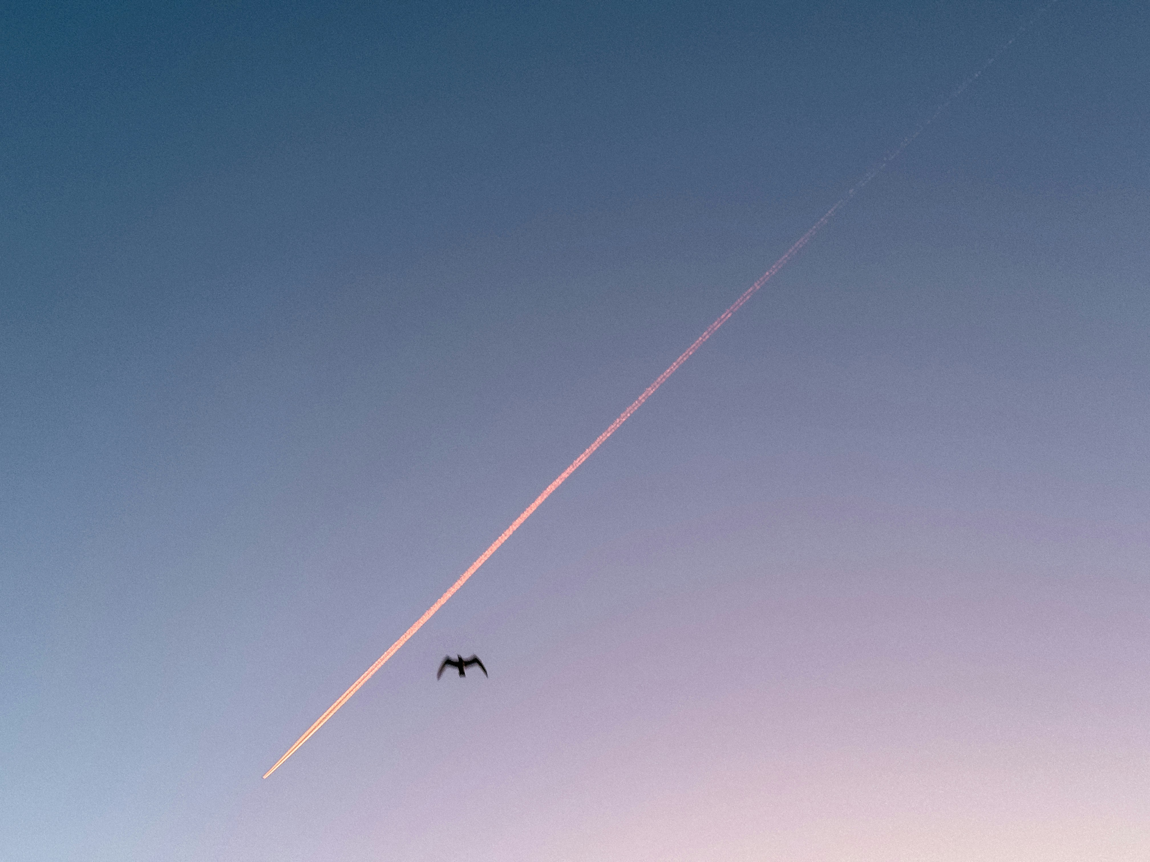 A plane flying in the sky with a contrail in the background
