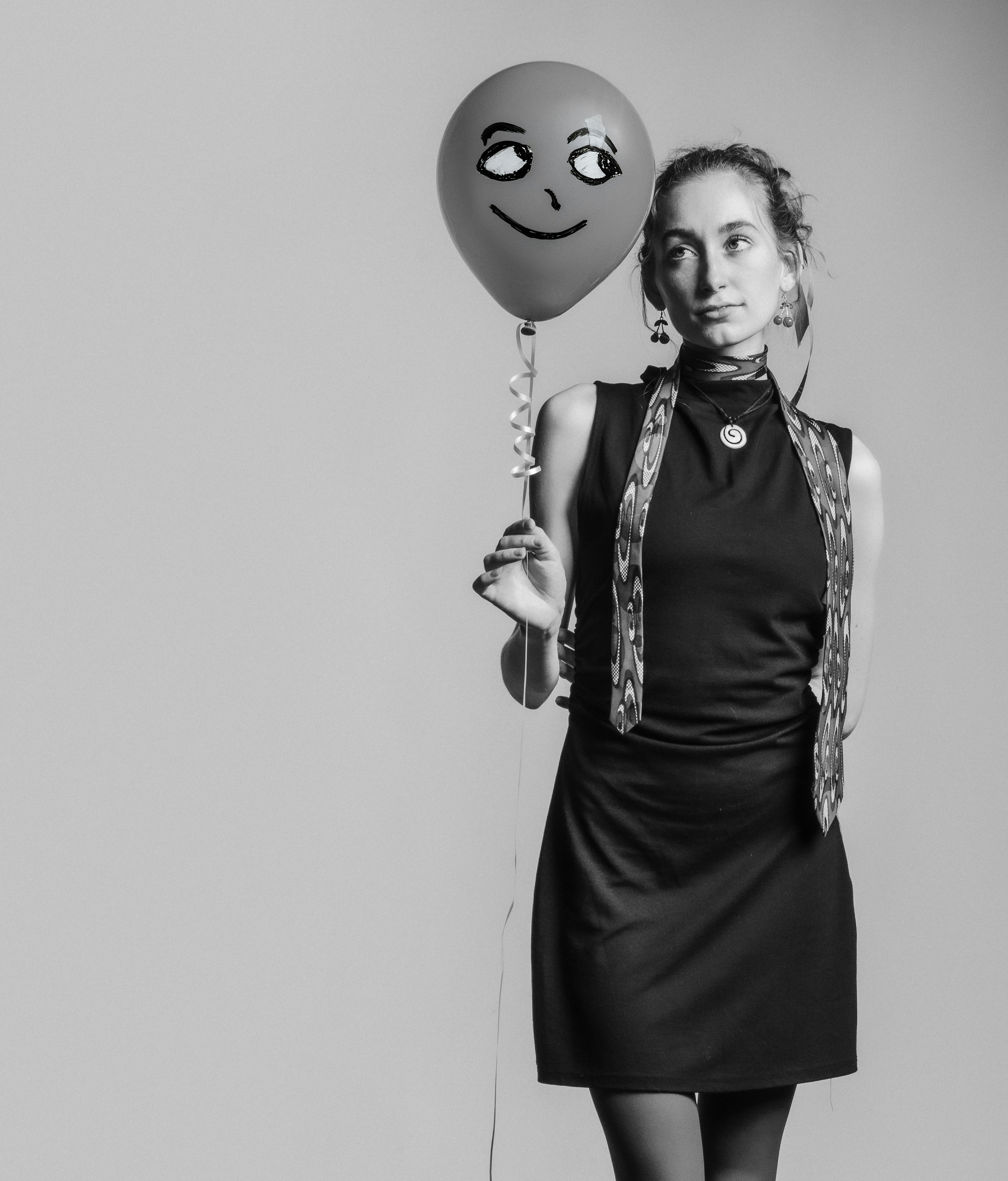 A woman holding a balloon with a smiley face on it