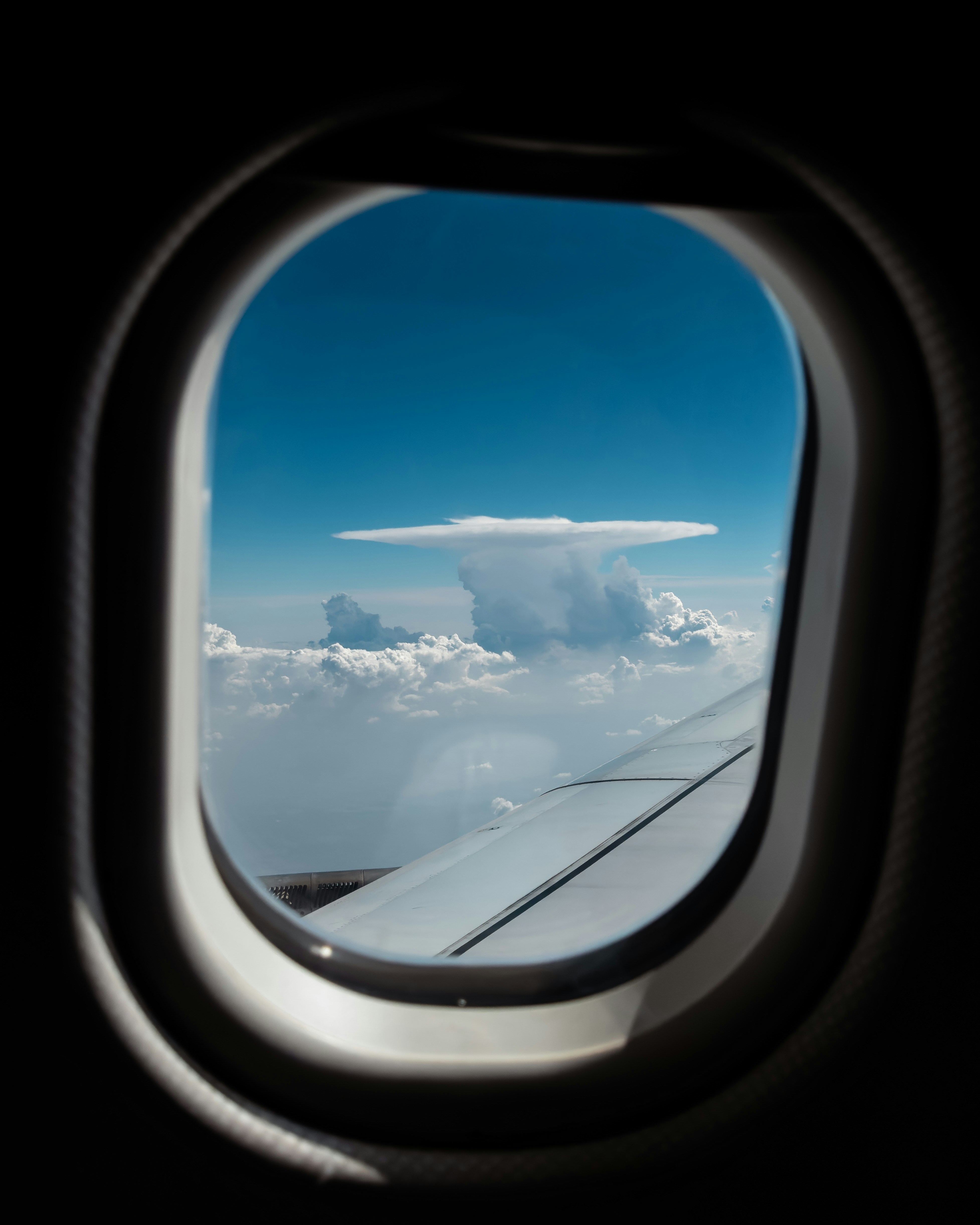 An airplane window with a view of the clouds