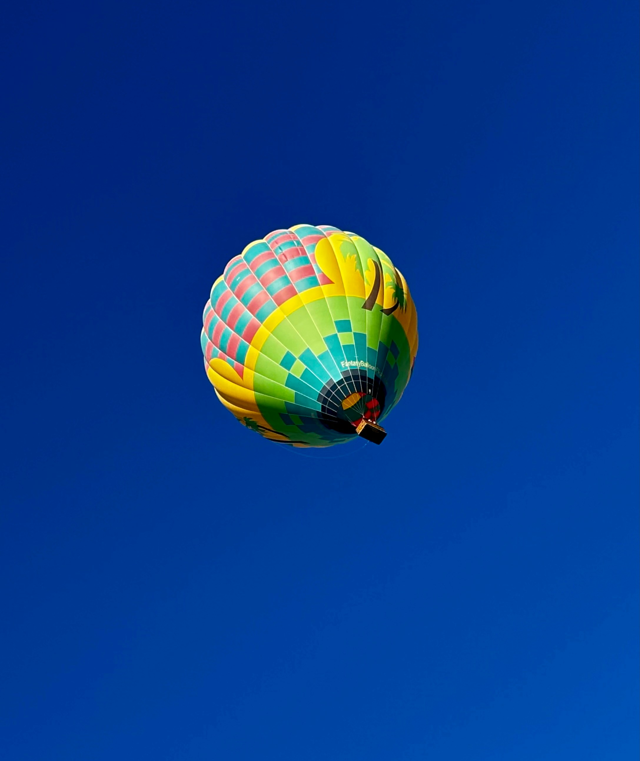 A colorful hot air balloon flying through a blue sky