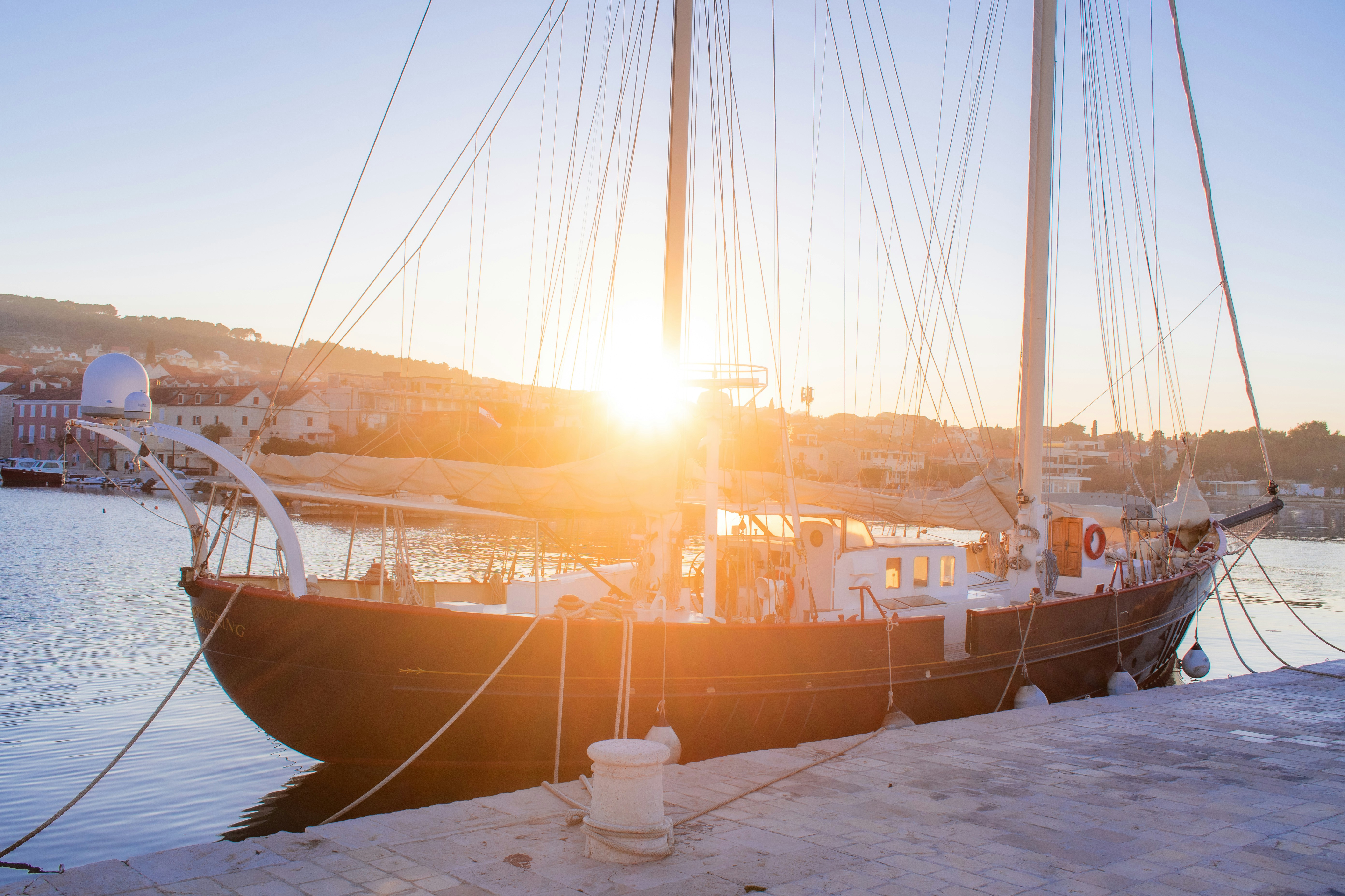 A boat is docked at a dock with the sun setting