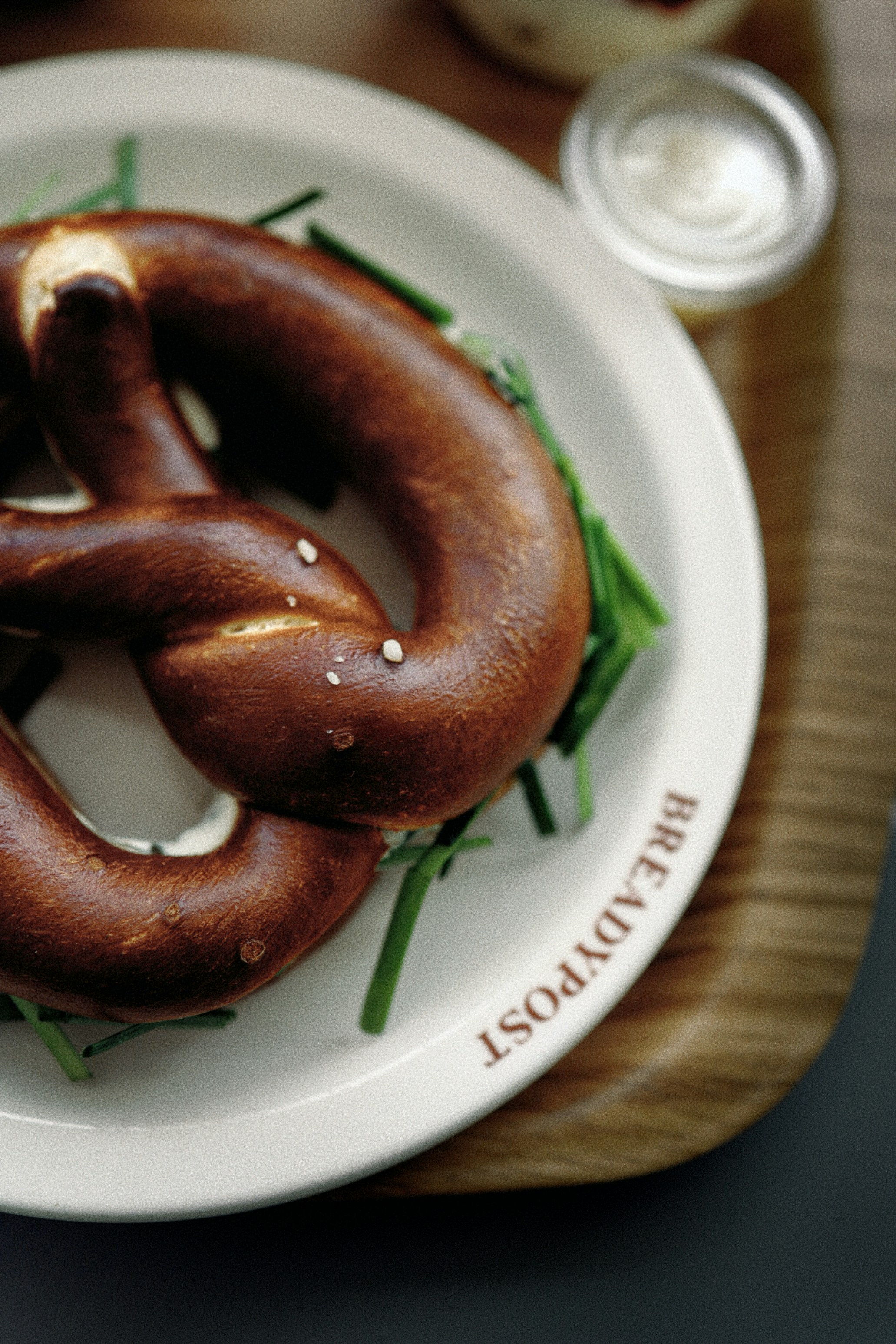 A white plate topped with a pretzel on top of a wooden table
