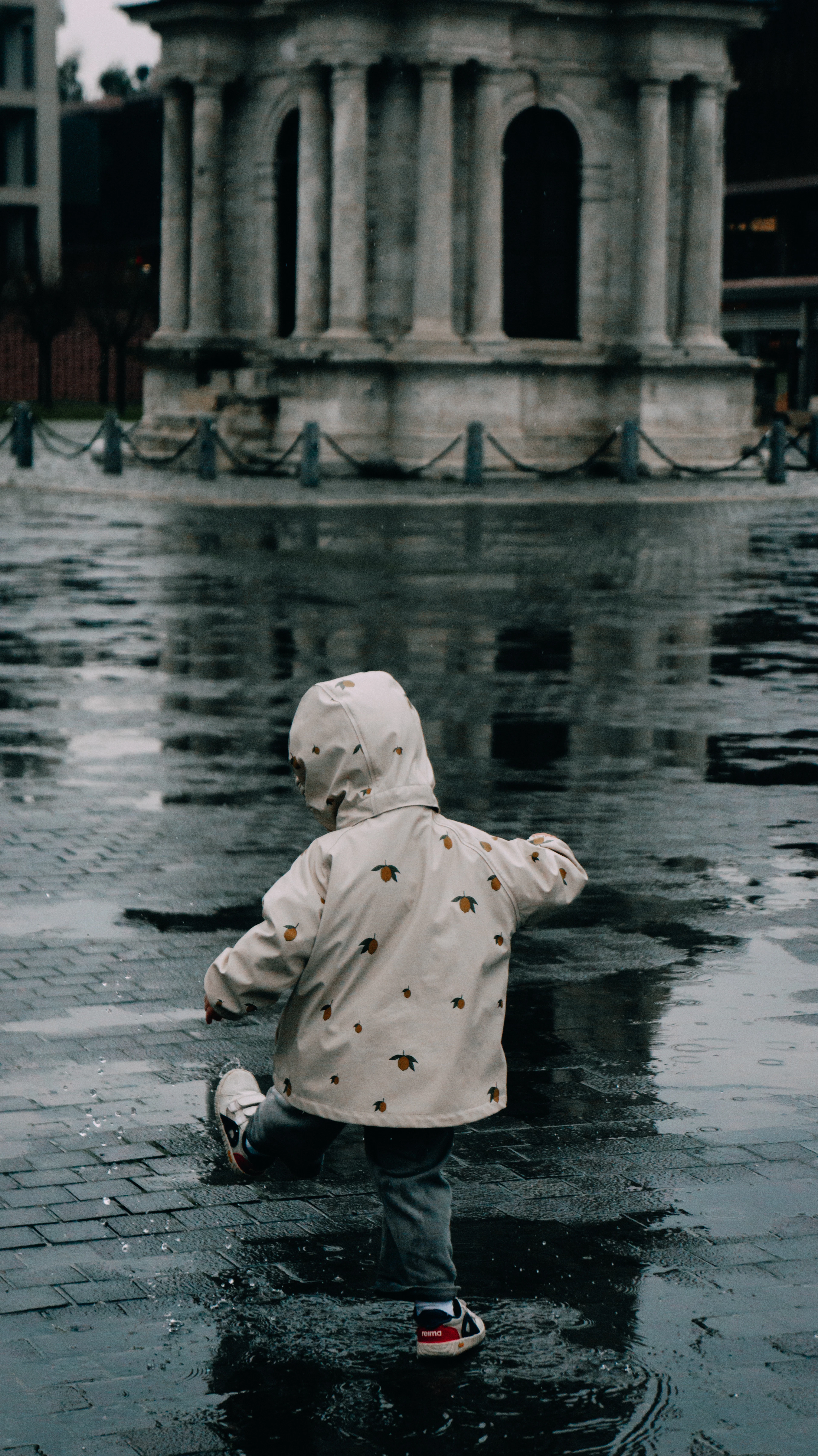 A small child standing in a puddle in the rain