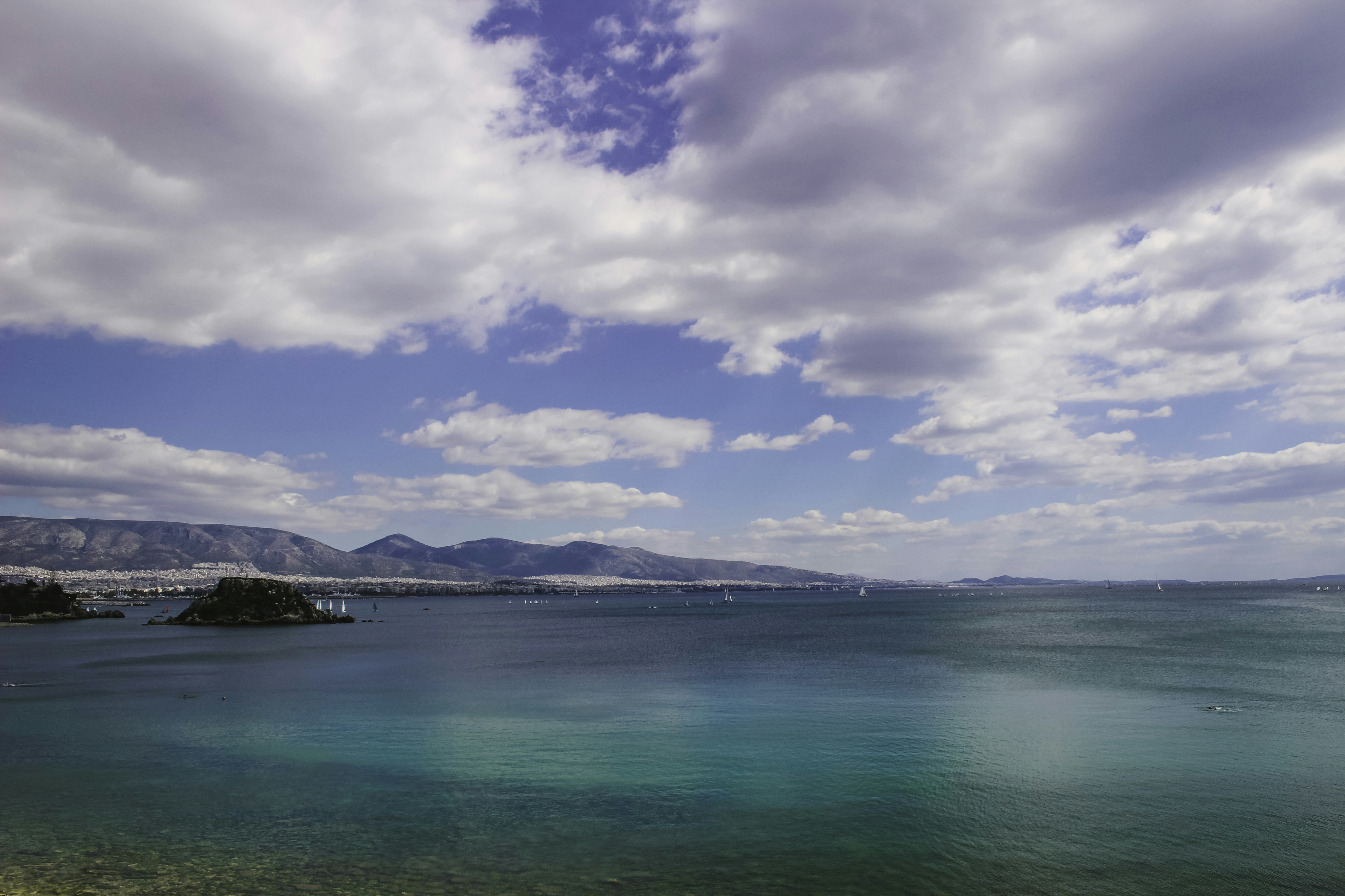 A body of water surrounded by mountains and clouds