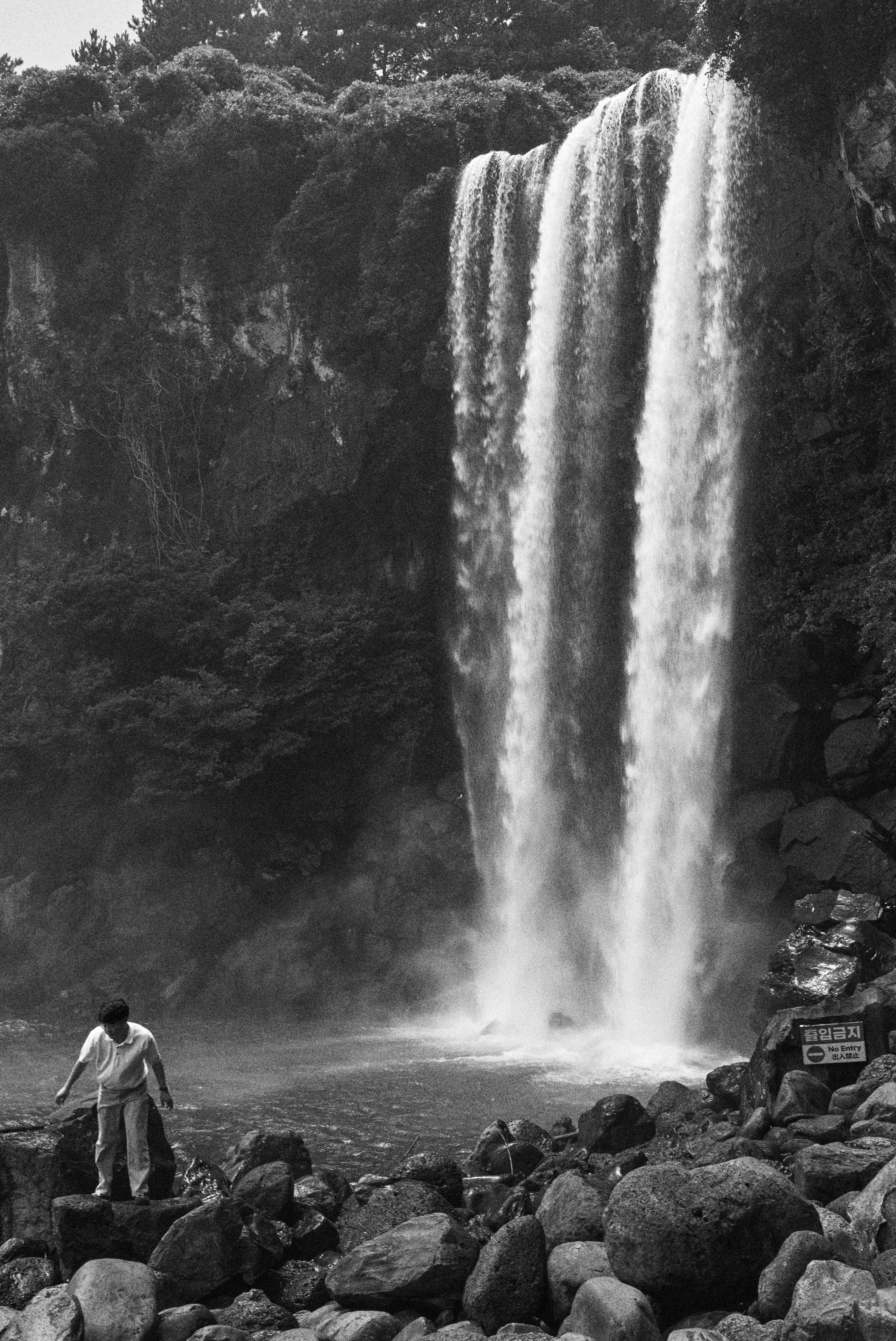 Una foto in bianco e nero di un uomo in piedi davanti a una cascata