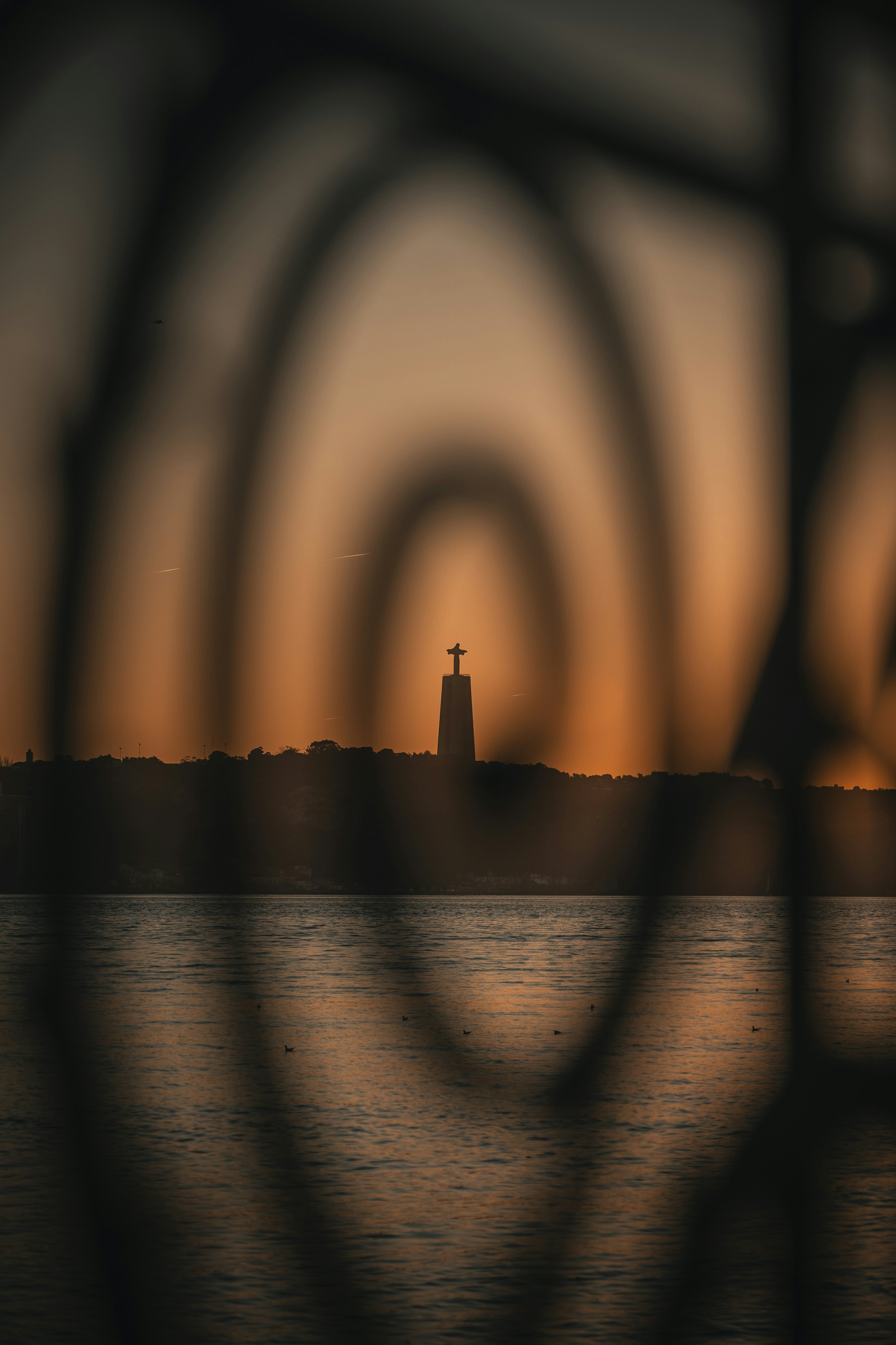 A view of a lighthouse through a wire fence