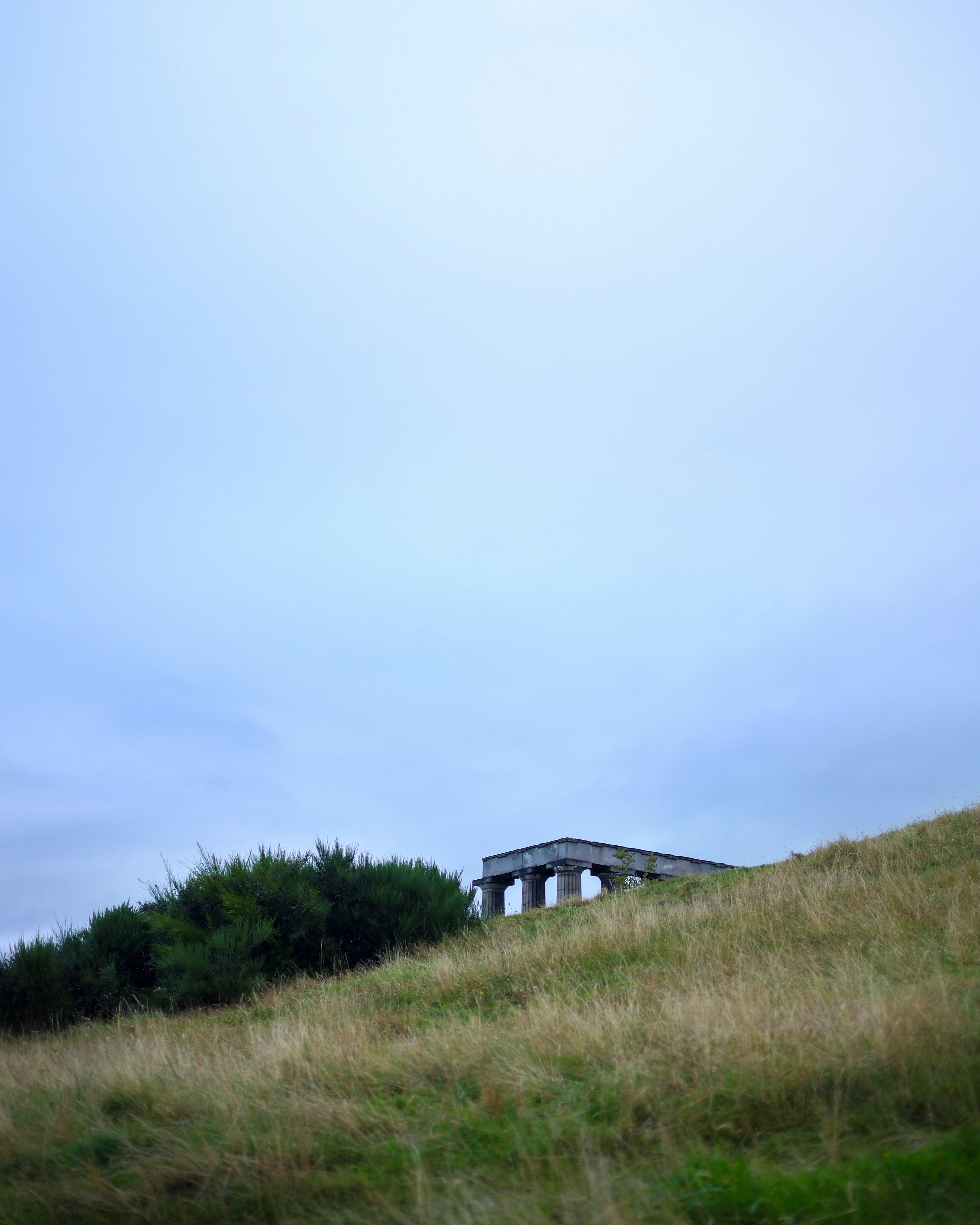 Ein grasbewachsener Hügel mit einem Haus auf dem Gipfel