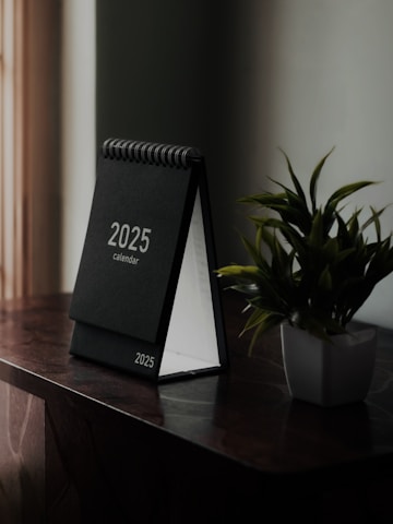 A desk with a desk calendar and a potted plant
