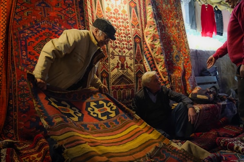 A group of men standing around a pile of rugs