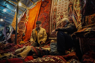 A man sitting on a bed surrounded by rugs