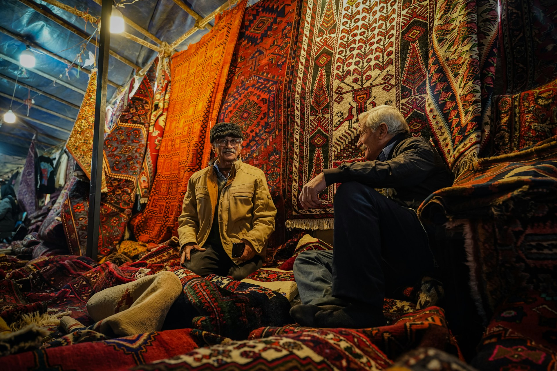 A man sitting on a bed surrounded by rugs