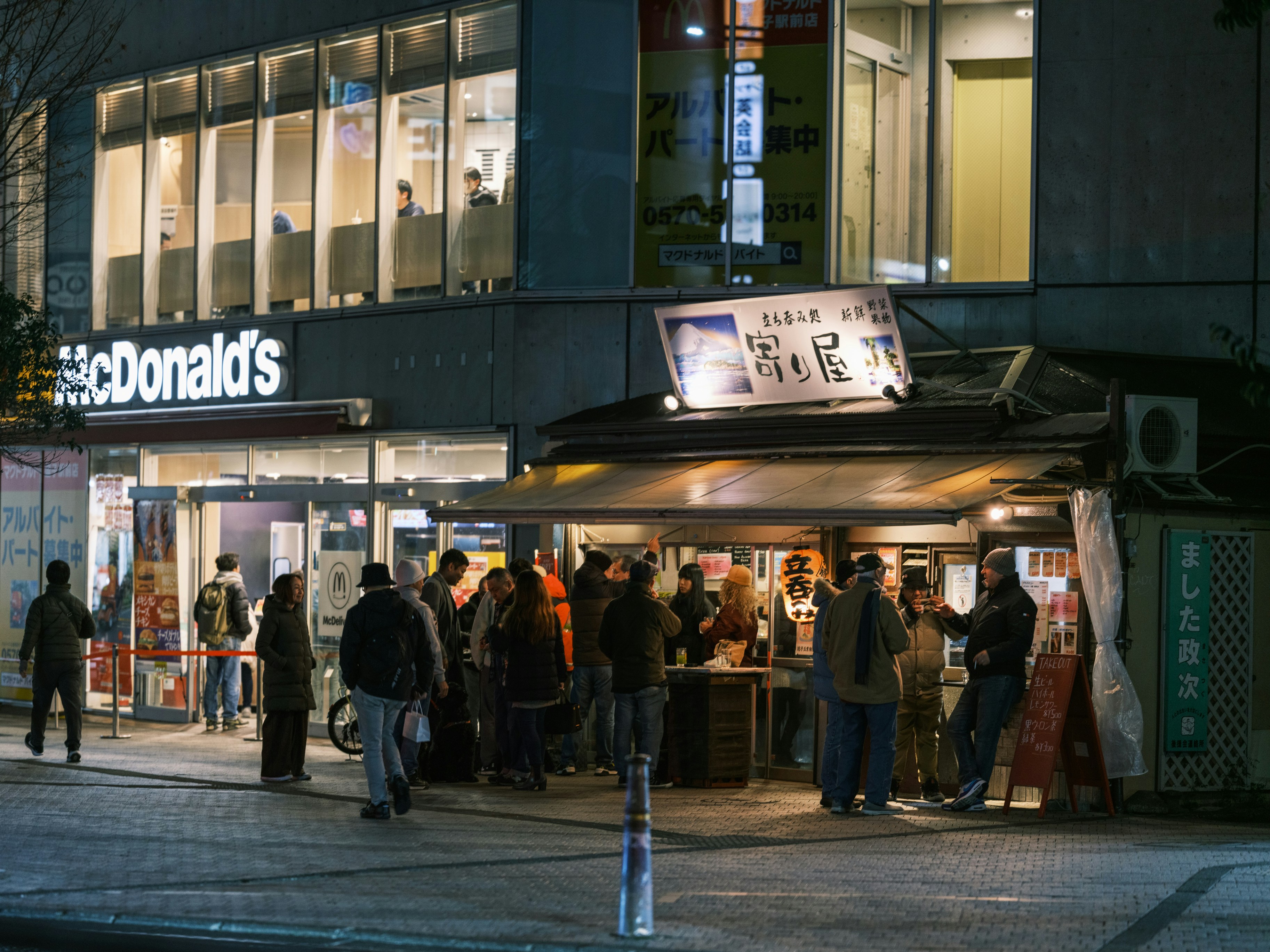 A group of people standing outside of a store at night