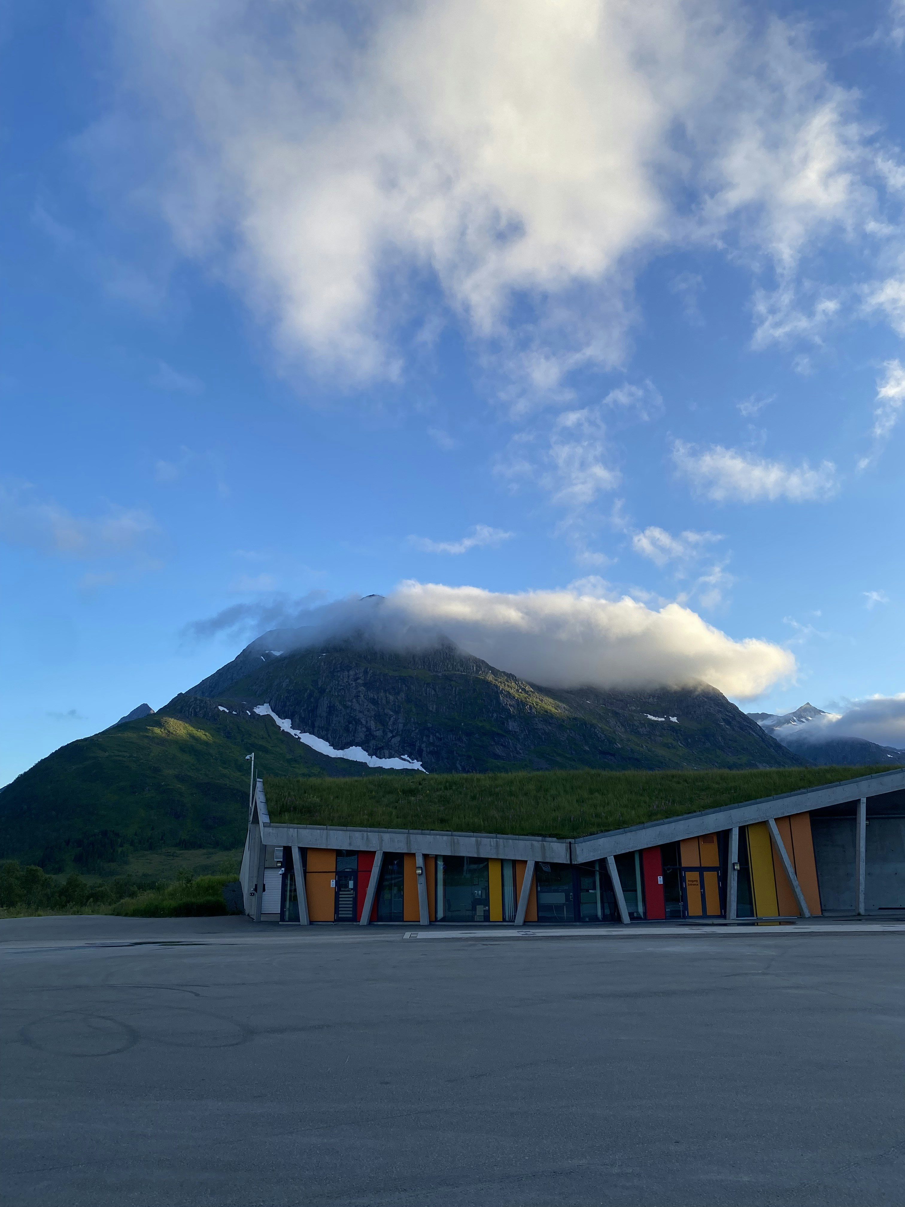 A building with a green roof and a mountain in the background